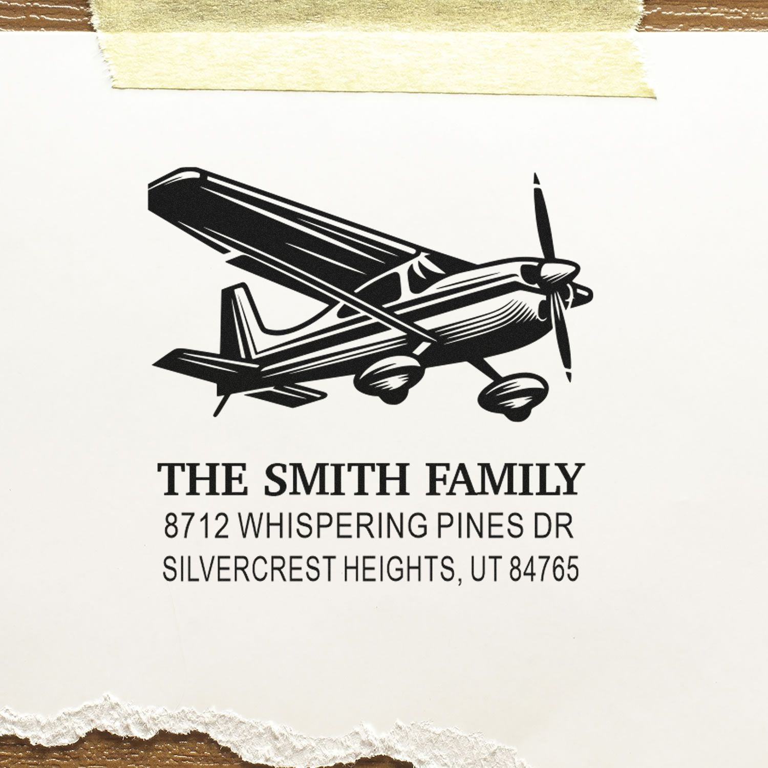Custom return address stamp with black airplane illustration and The Smith Family address on white paper.