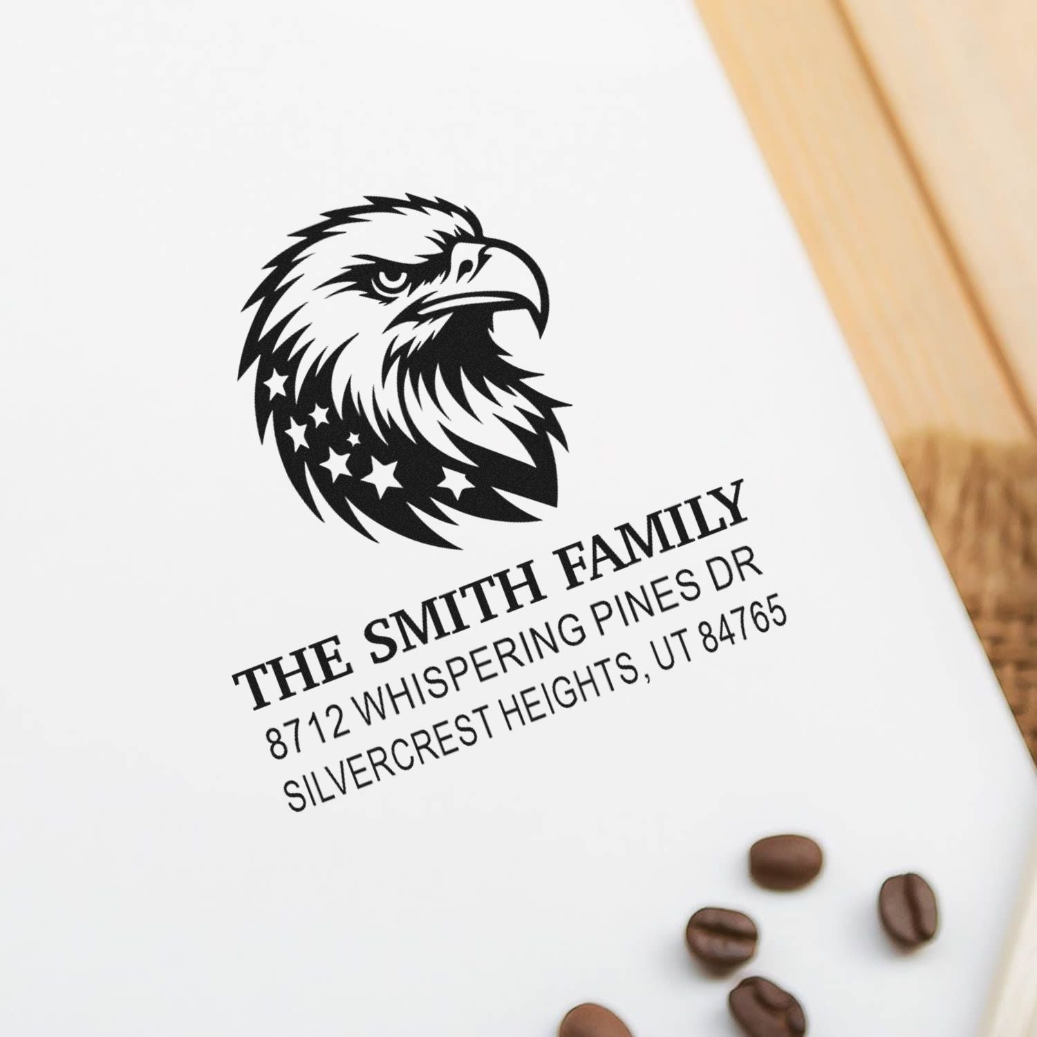 Custom family address stamp with eagle logo on white card, reading The Smith Family, beside coffee beans on a wooden table.