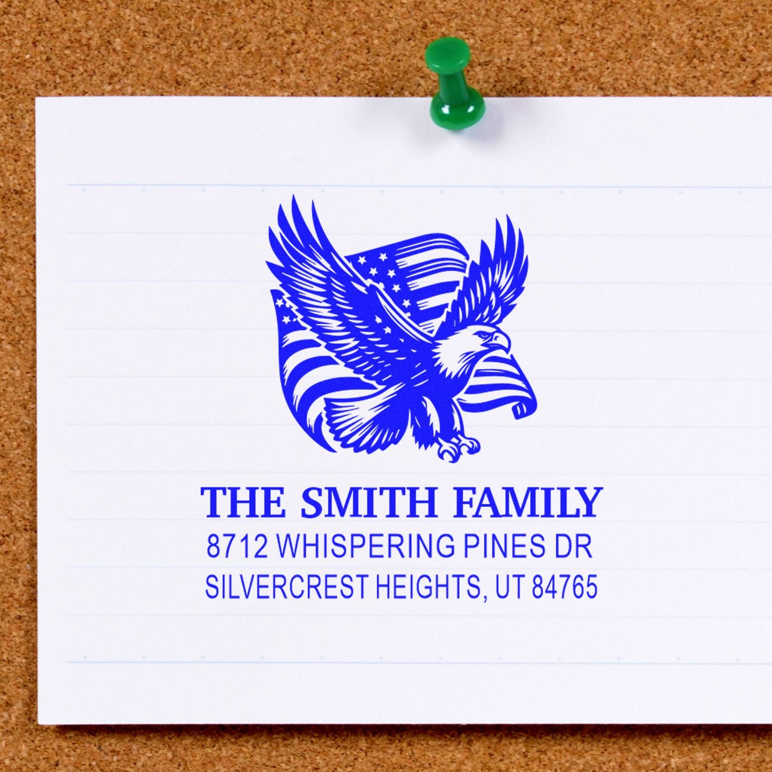 Custom family address stamp with eagle and American flag design, printed on paper pinned to a corkboard.