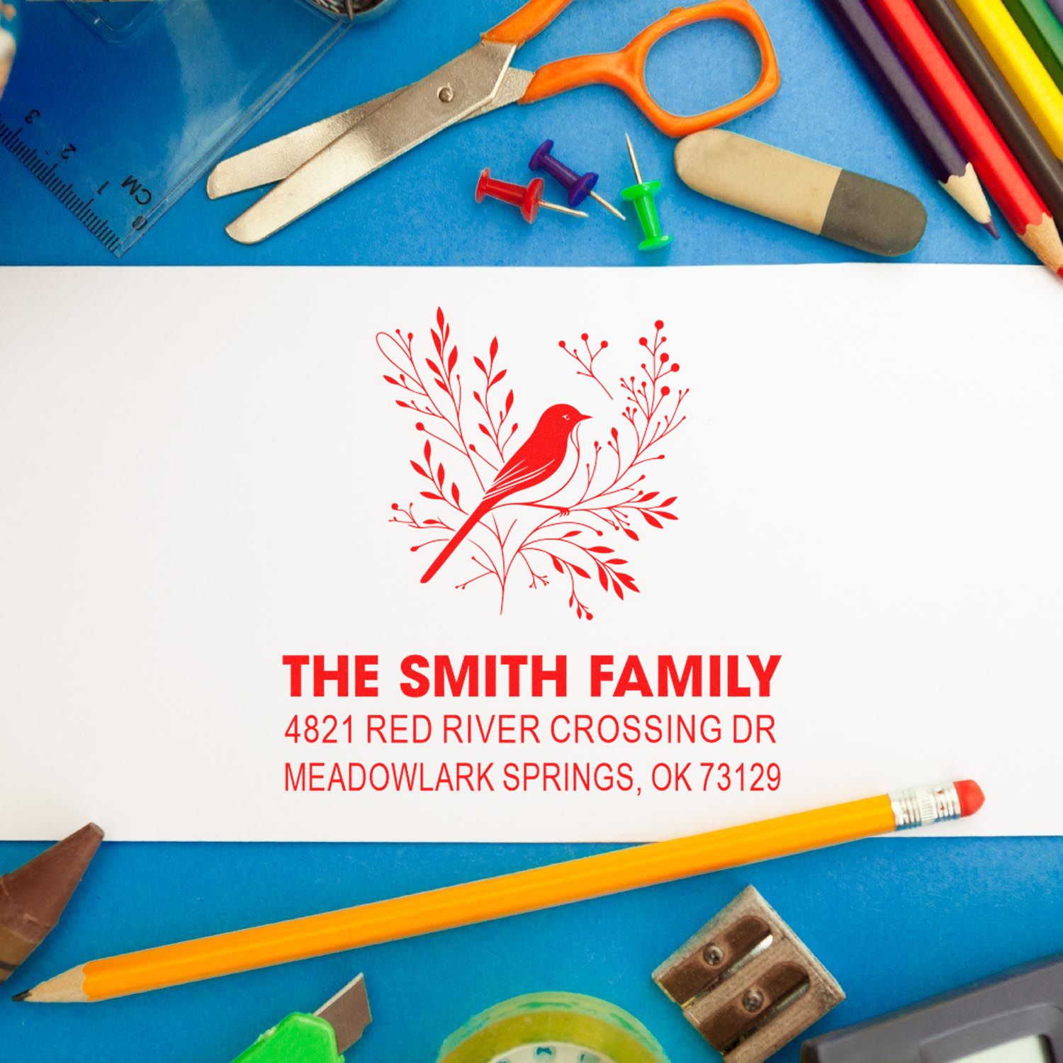 Custom rubber address stamp with bird design for The Smith Family, showing personalized name and mailing address in red ink on white stationery.