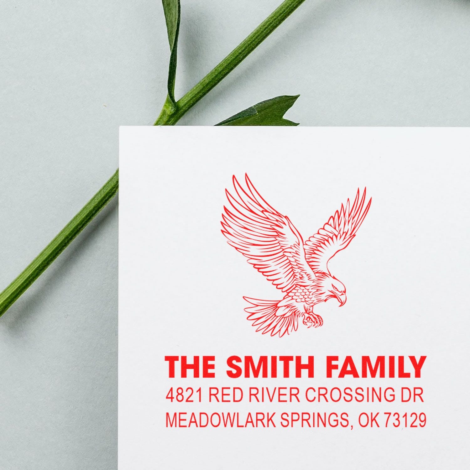 Custom red address rubber stamp with eagle emblem, The Smith Family name, and return address for Meadowlark Springs, OK 73129 for envelopes.