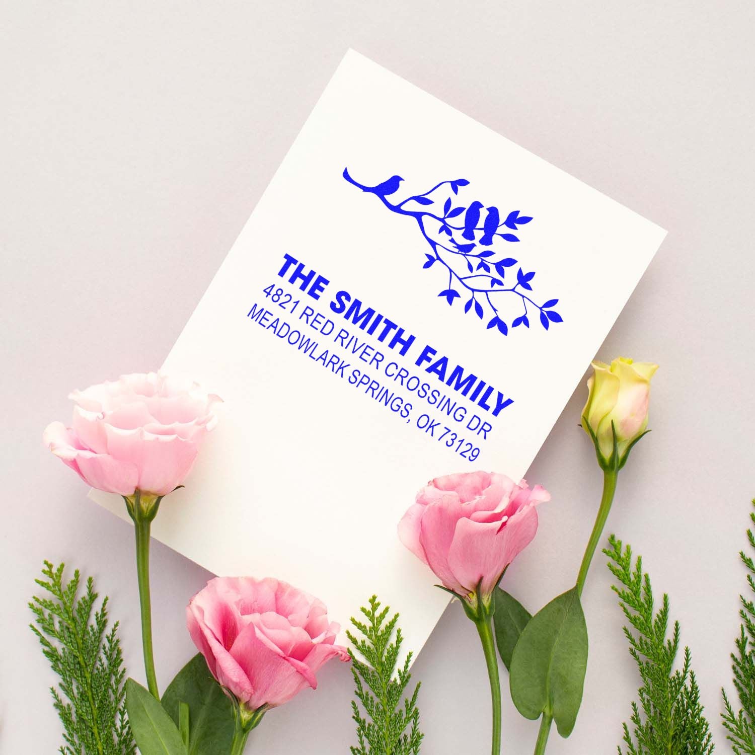 Custom address rubber stamp with bird and branch design, blue ink impression, featuring The Smith Family name and Meadowlark Springs address