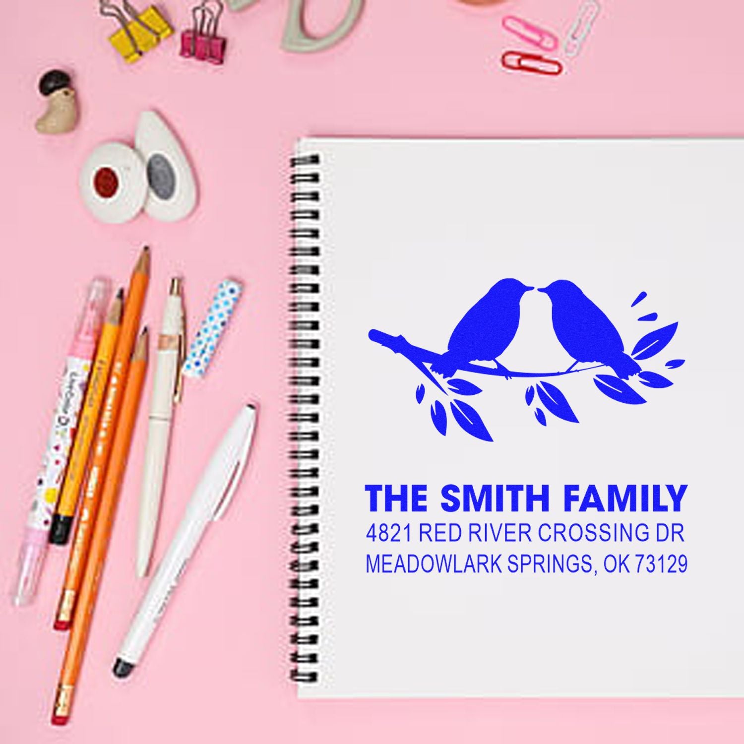 Custom return address rubber stamp with blue bird design, family name and address on notebook, ideal for stationery, weddings, and mailing labels