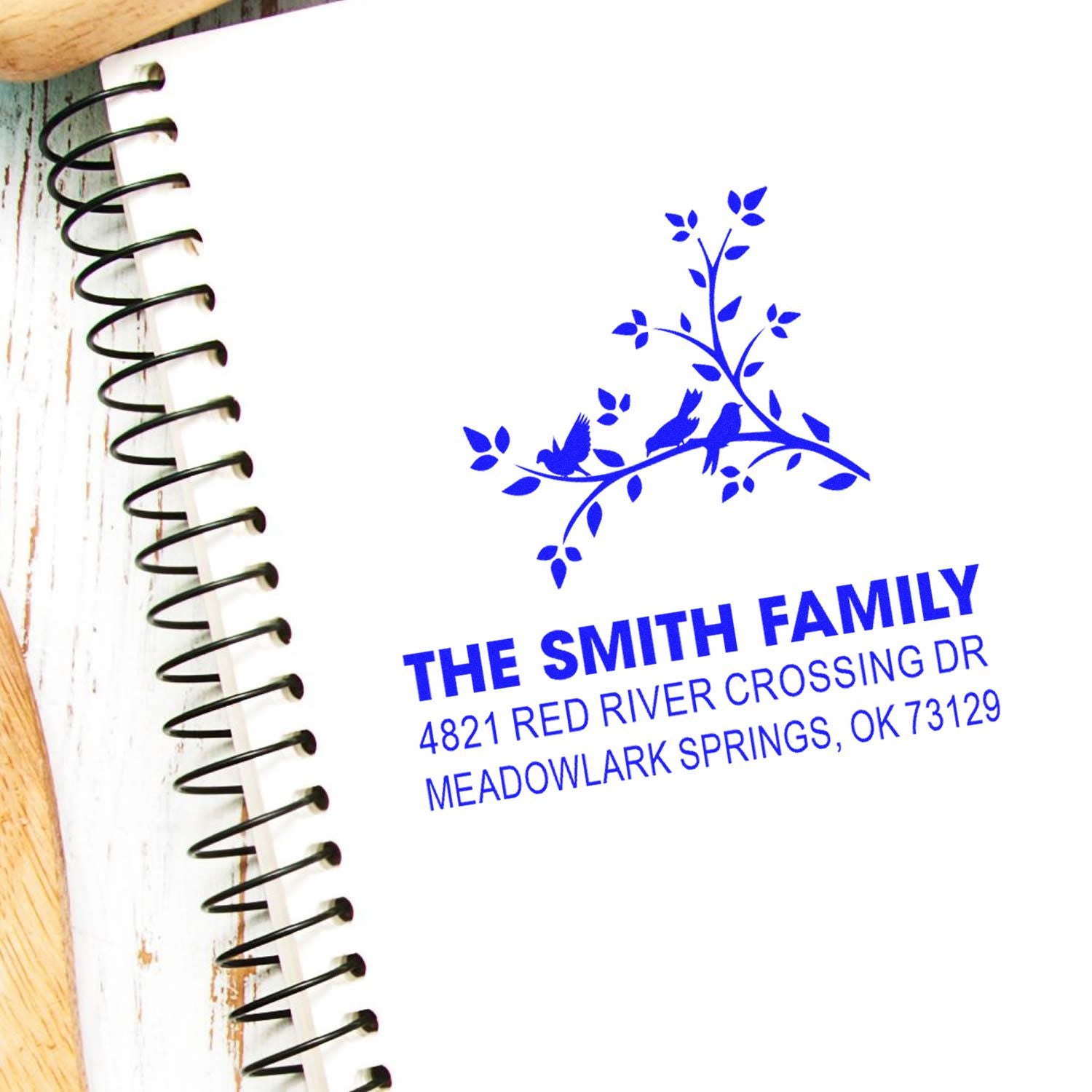 Personalized rubber address stamp with bird branch design, blue ink impression, featuring The Smith Family and custom Meadowlark Springs address.