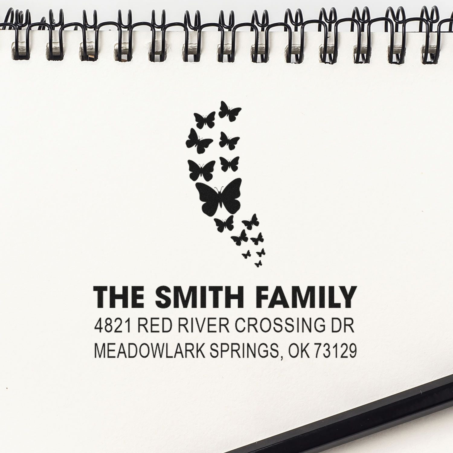 Custom butterfly family address rubber stamp impression with The Smith Family name and Meadowlark Springs, OK return address on notebook page.