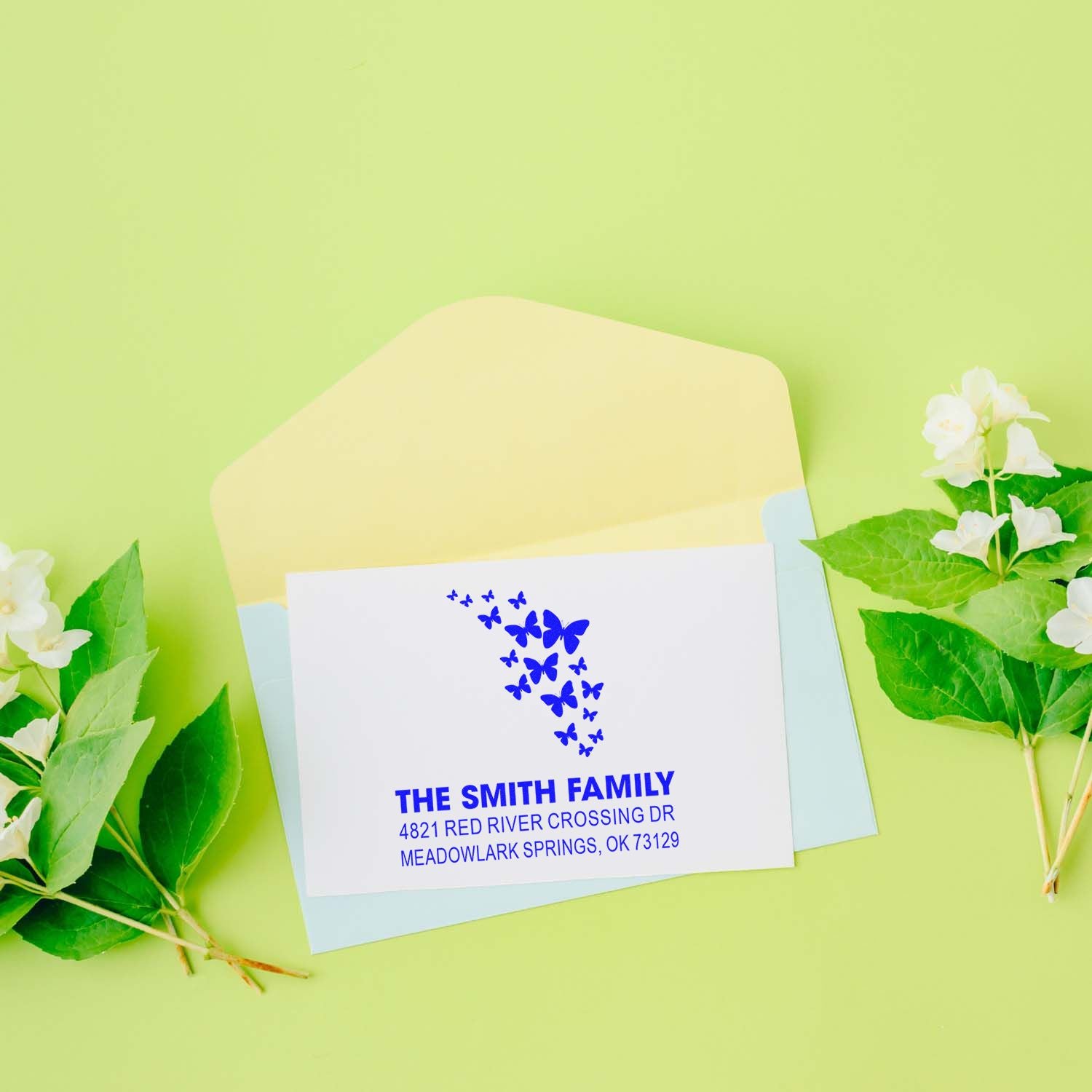 Custom butterfly return address stamp with The Smith Family name and personalized mailing address on a white envelope, blue ink impression.