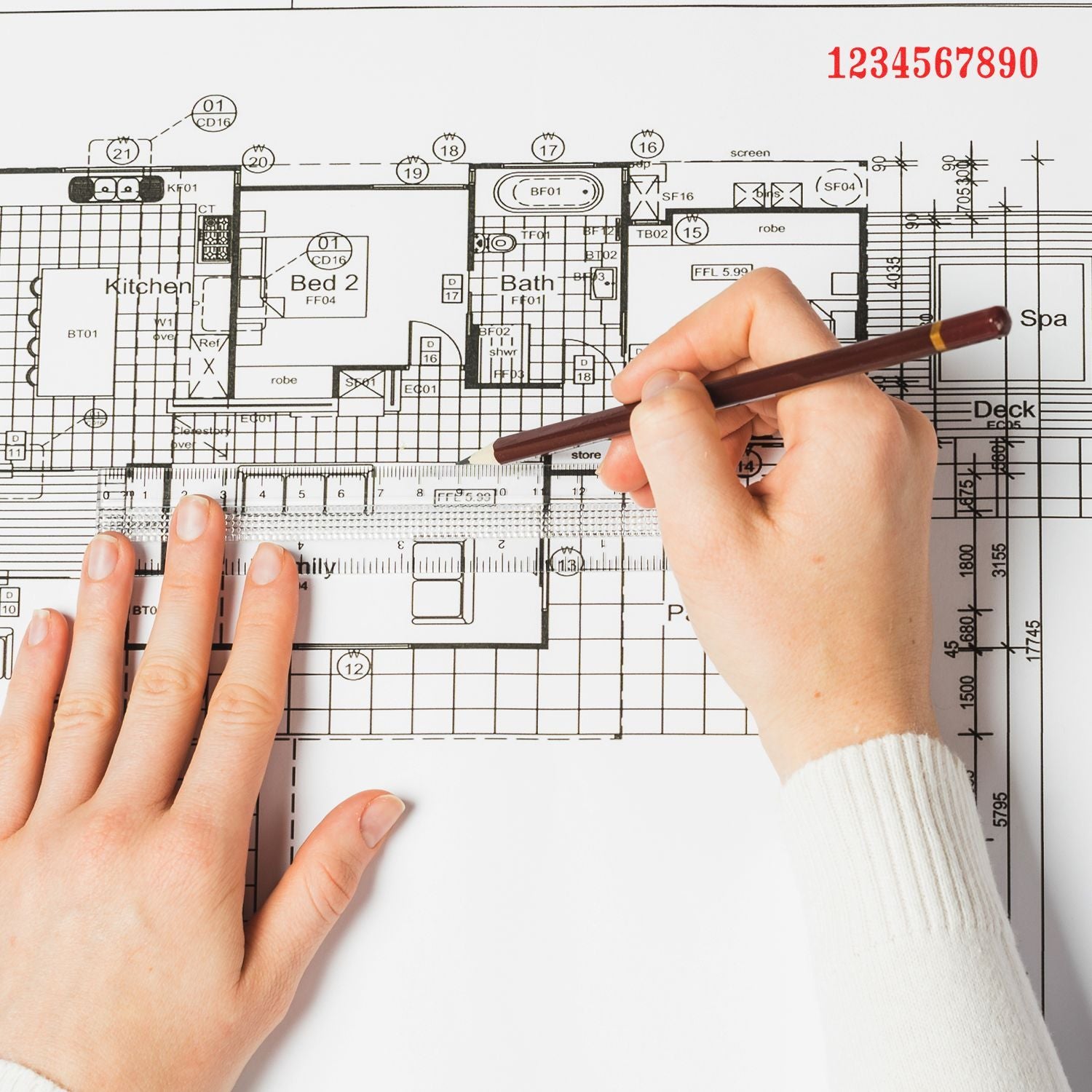 Hands using a pencil and ruler on an architectural floor plan blueprint for home design and construction planning.