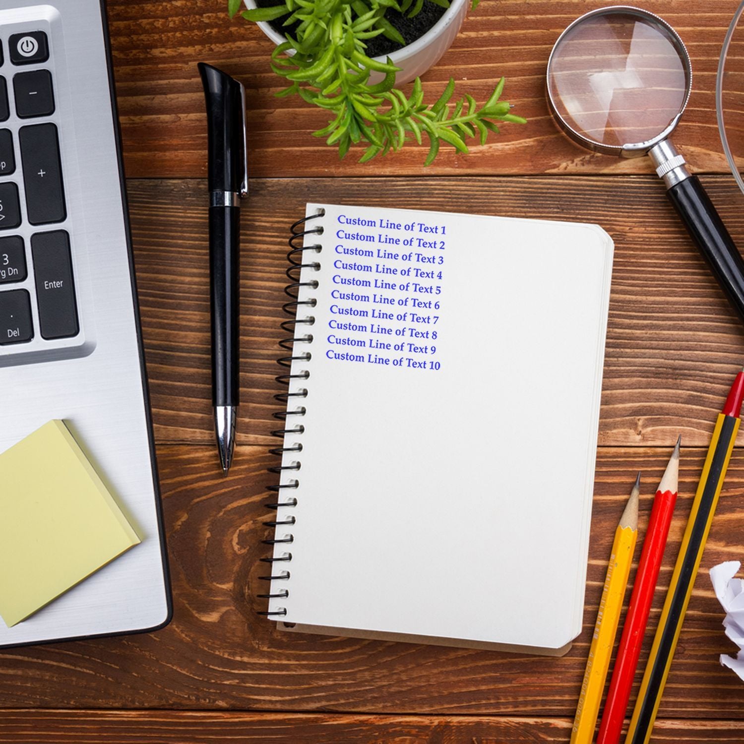 Customizable notebook template for writing multiple text lines, with pens, magnifying glass, and plant on wooden desk.