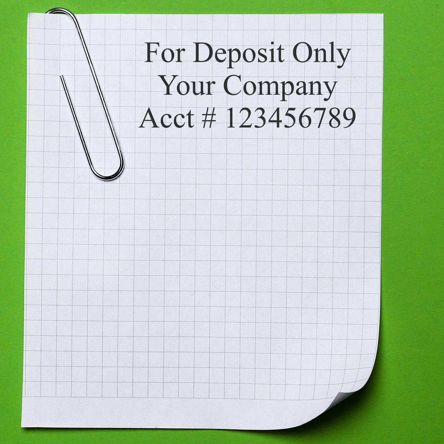 For deposit only company check stub with paperclip and account number on graph paper background.