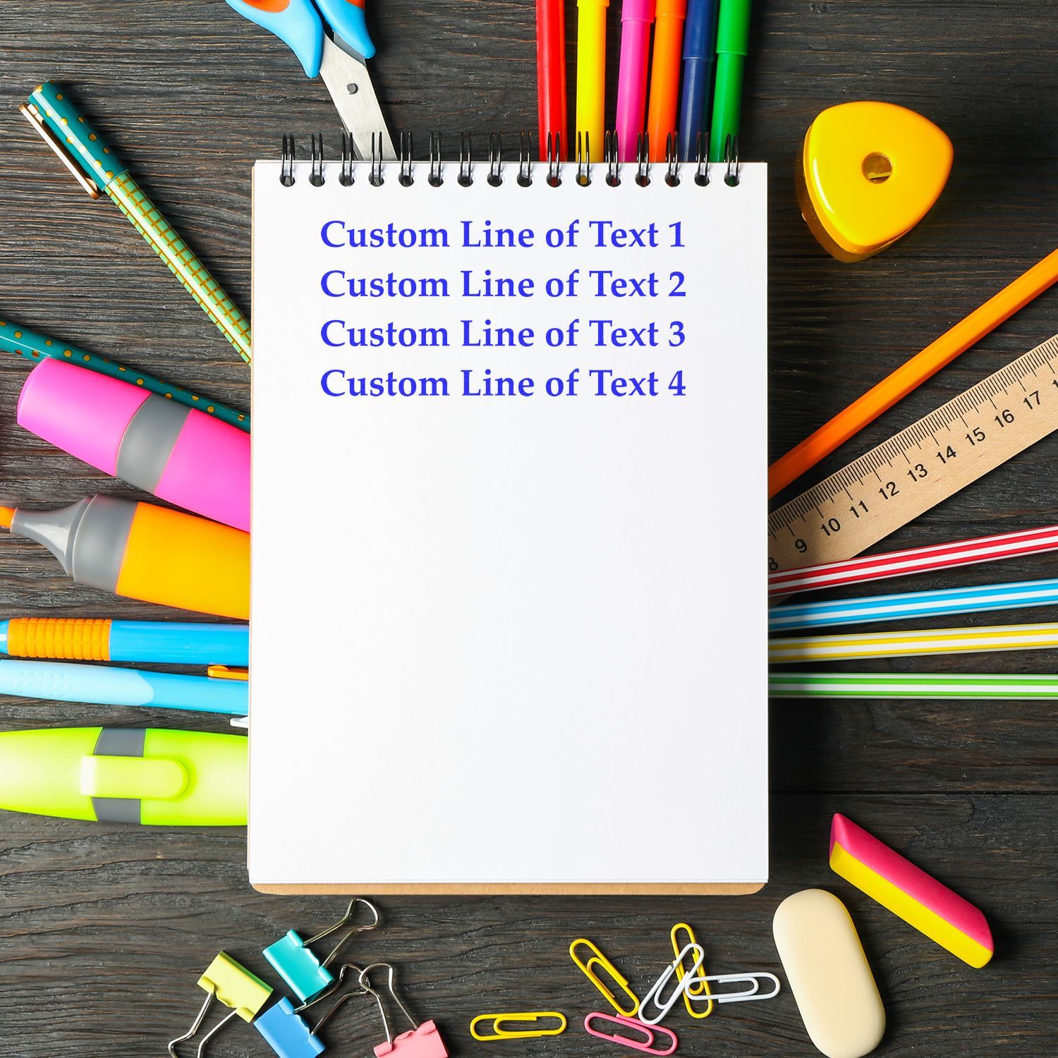 Notebook template with custom text lines surrounded by colorful school supplies on a dark wooden desk.
