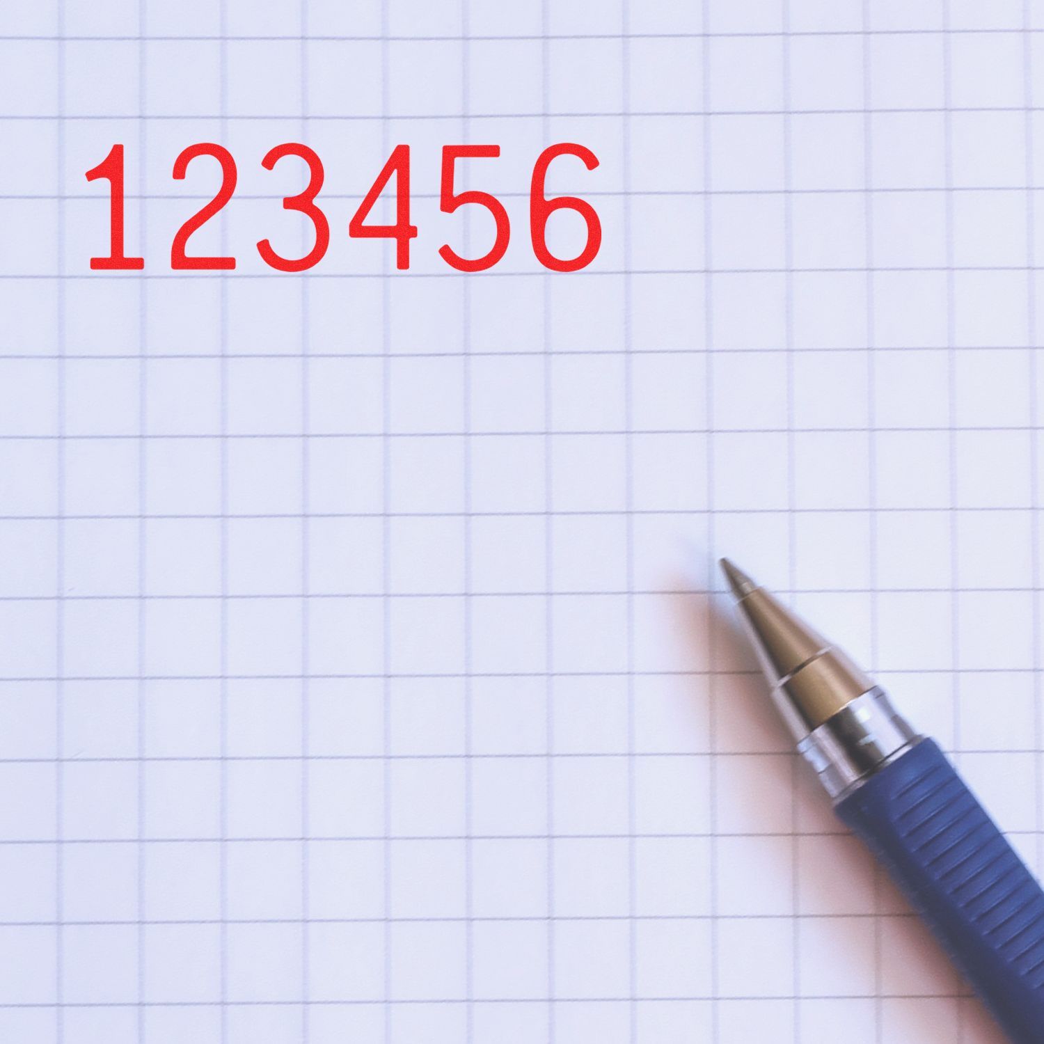 Red 123456 numbers on graph paper with a blue pen, close-up of a writing and math concept.