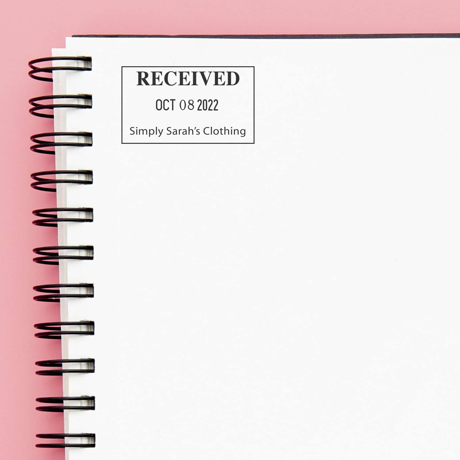 Spiral-bound notebook page with Received stamp dated Oct 08 2022 for Simply Sarahs Clothing on a pink background.