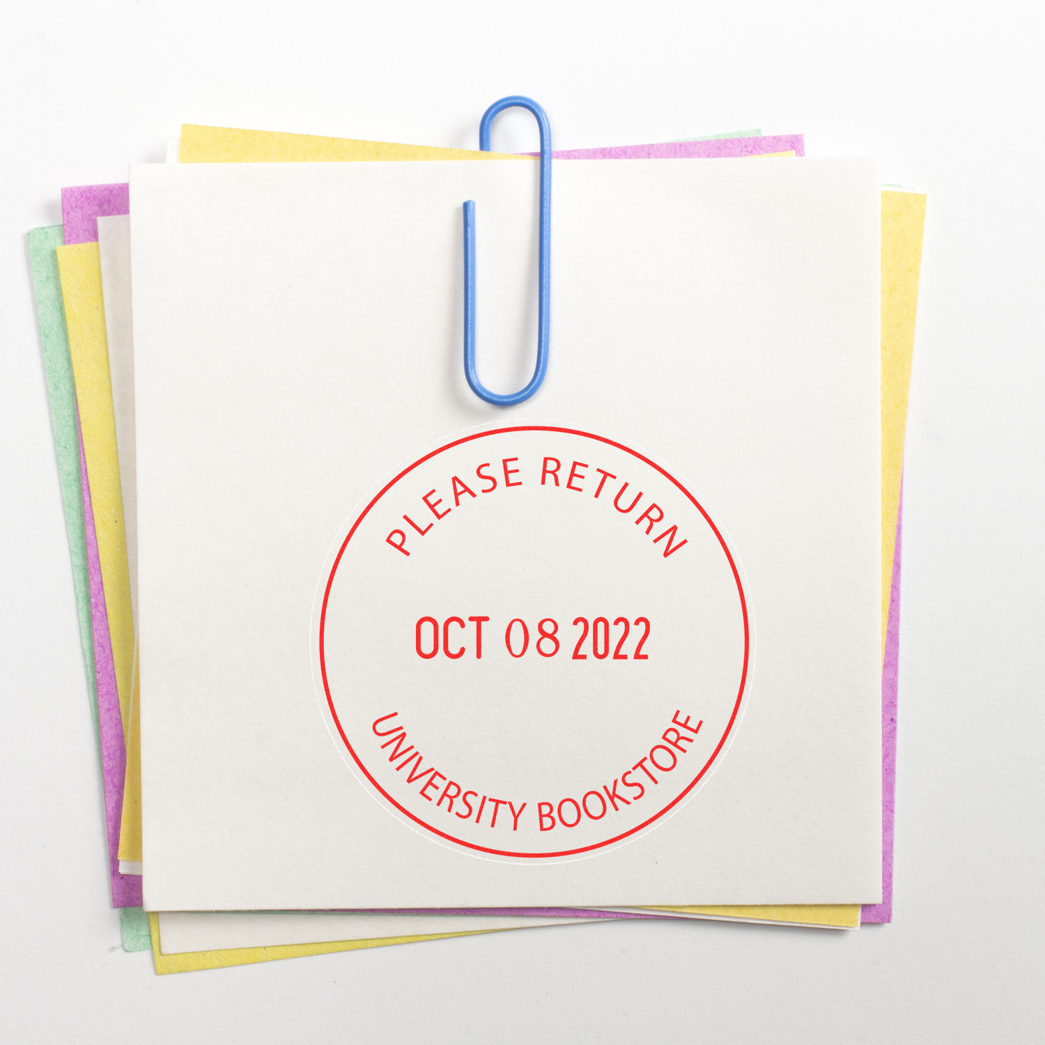 Stack of library books return slip with paperclip and Please Return university bookstore stamp on colorful paper tabs