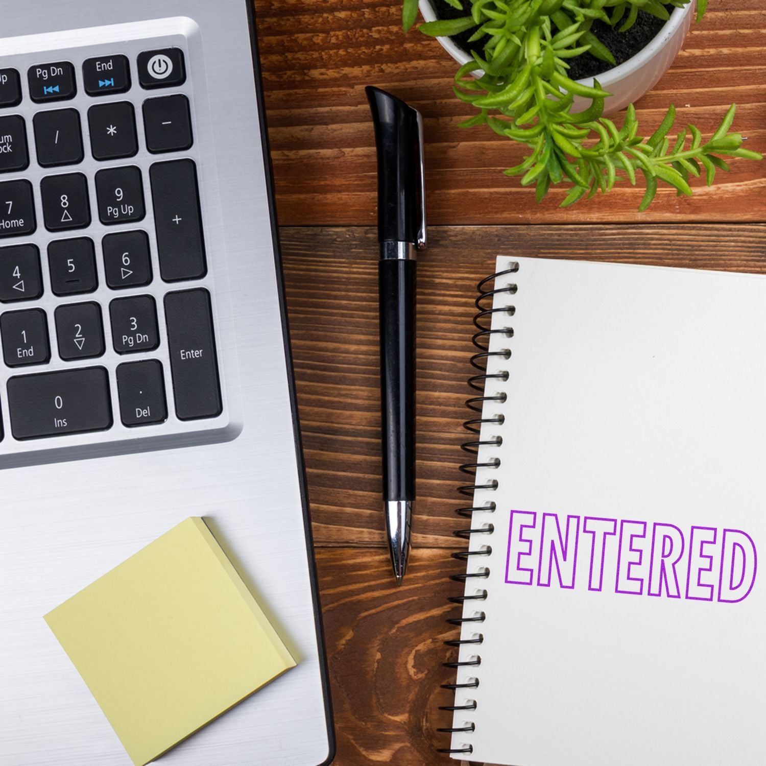 Data entry productivity scene: laptop keyboard, pen, notebook and sticky notes on desk with ENTERED text.