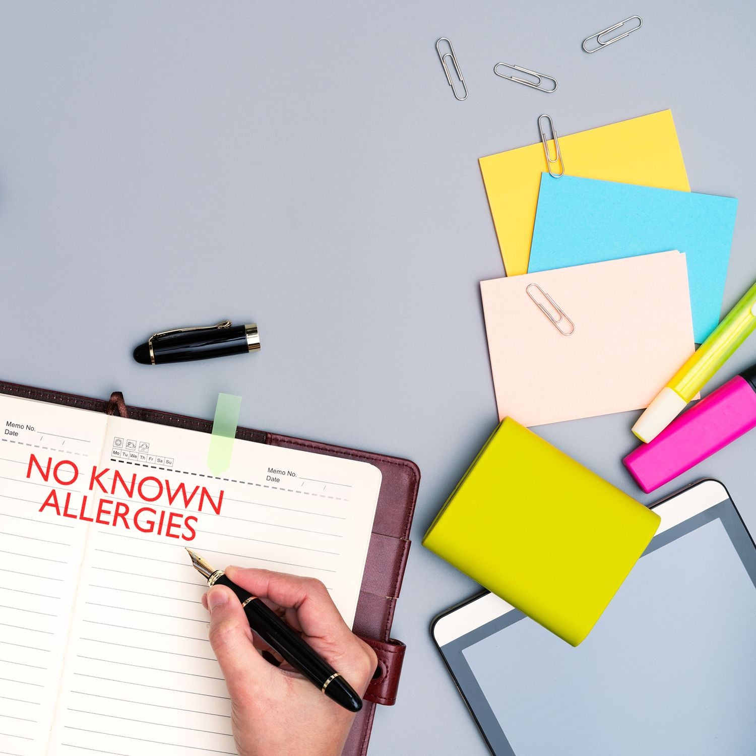 No known allergies medical record concept with notebook note, pens and colorful sticky tabs on desk for healthcare documentation.