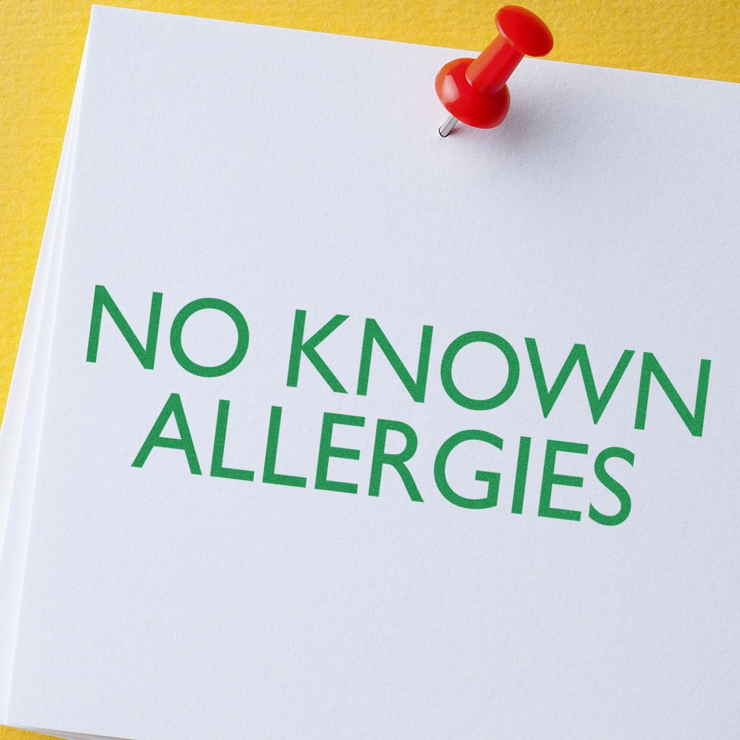 No known allergies notice pinned to medical paper with red pushpin, indicating allergy-free status for healthcare safety.