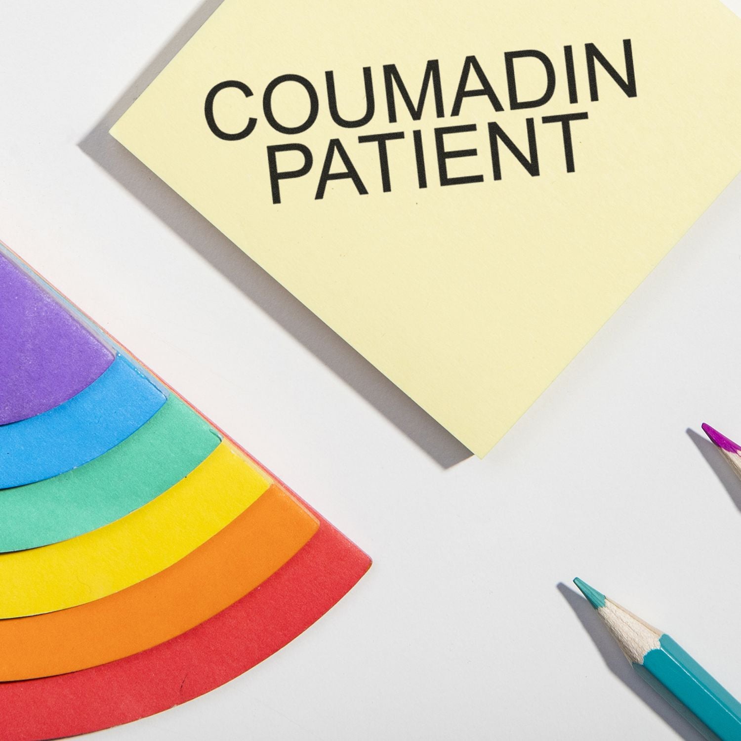 Coumadin patient safety sign on yellow paper with colored pencils, reminding anticoagulant medication precautions.