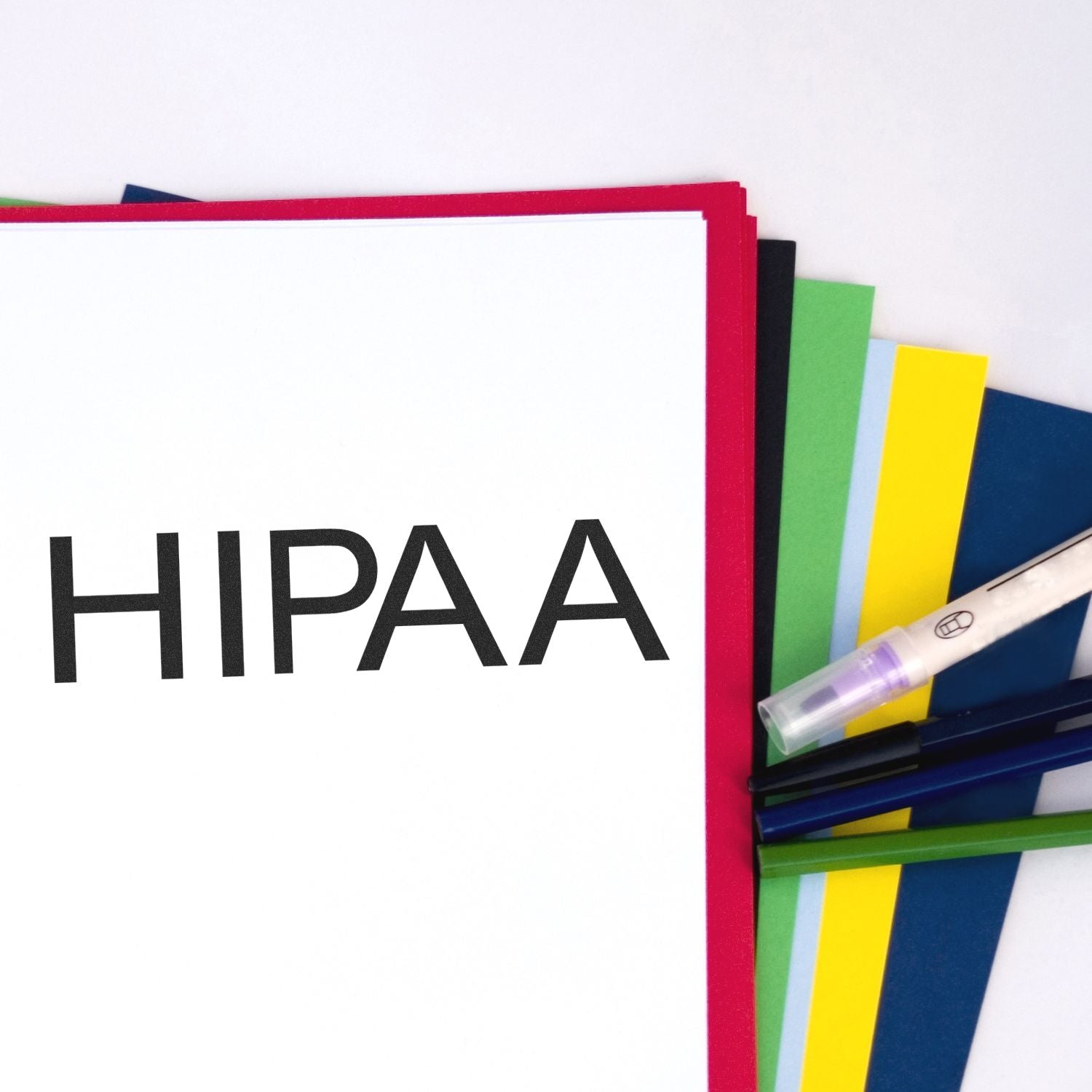 HIPAA compliance binder with colorful medical files and pen, showing healthcare privacy documentation organization.