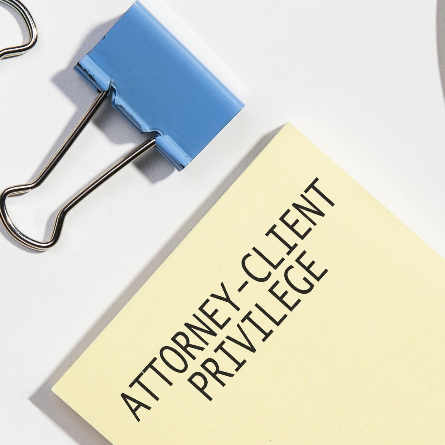 Blue binder clip holding an Attorney-Client Privilege document label, emphasizing legal confidentiality and privileged communication.