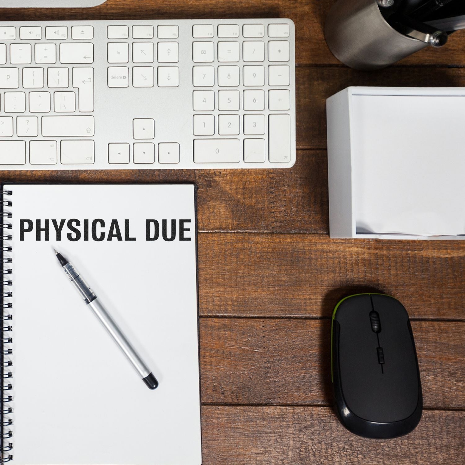 Office desk with laptop keyboard, mouse, and notebook labeled PHYSICAL DUE, suggesting physical due records and payment tracking.