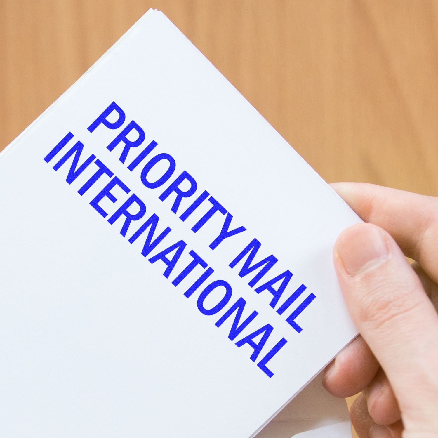 Hand holding Priority Delivery International shipping card on a white envelope for express international delivery service