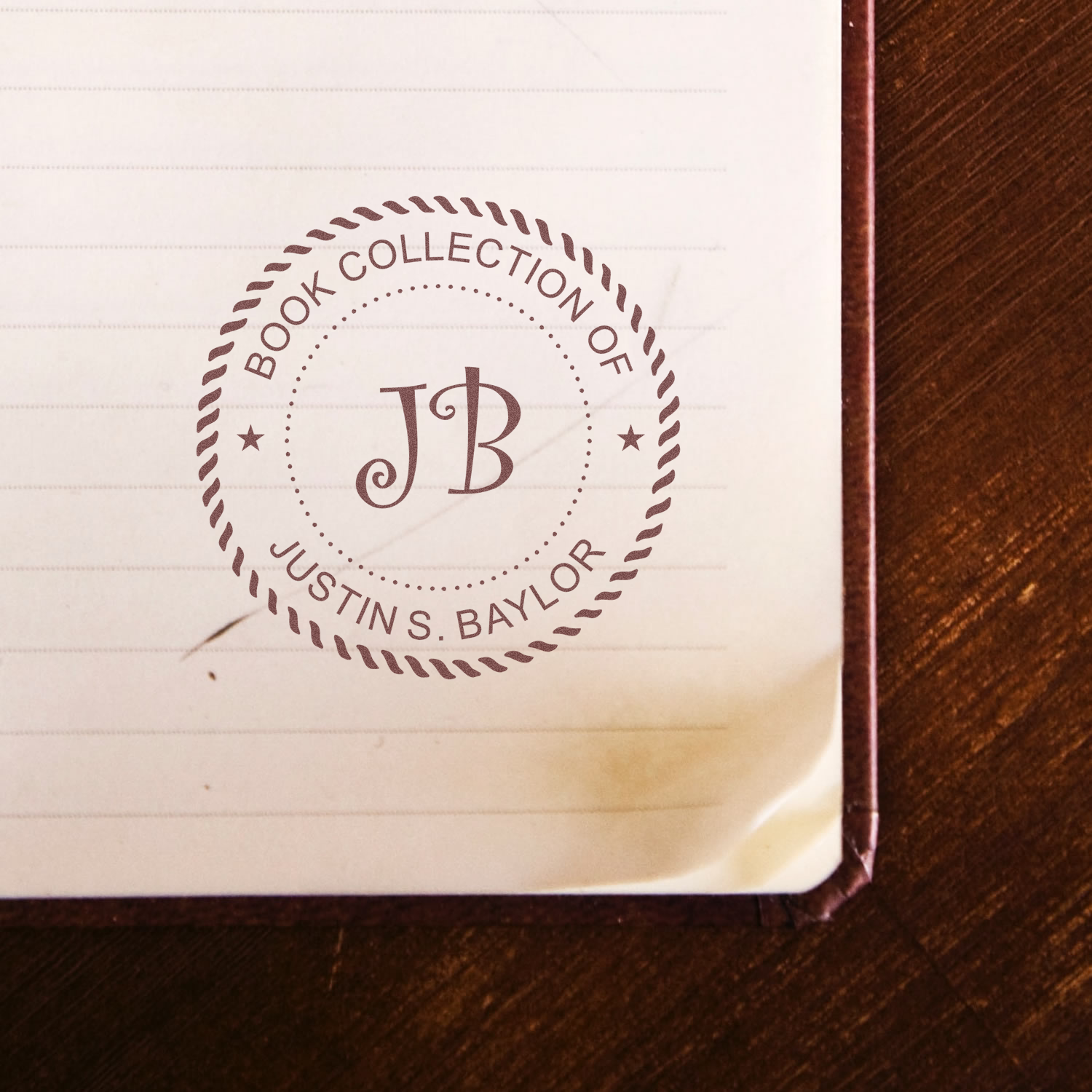 Personalized rubber book stamp with initials JB and name Justin S. Baylor for marking a book collection.