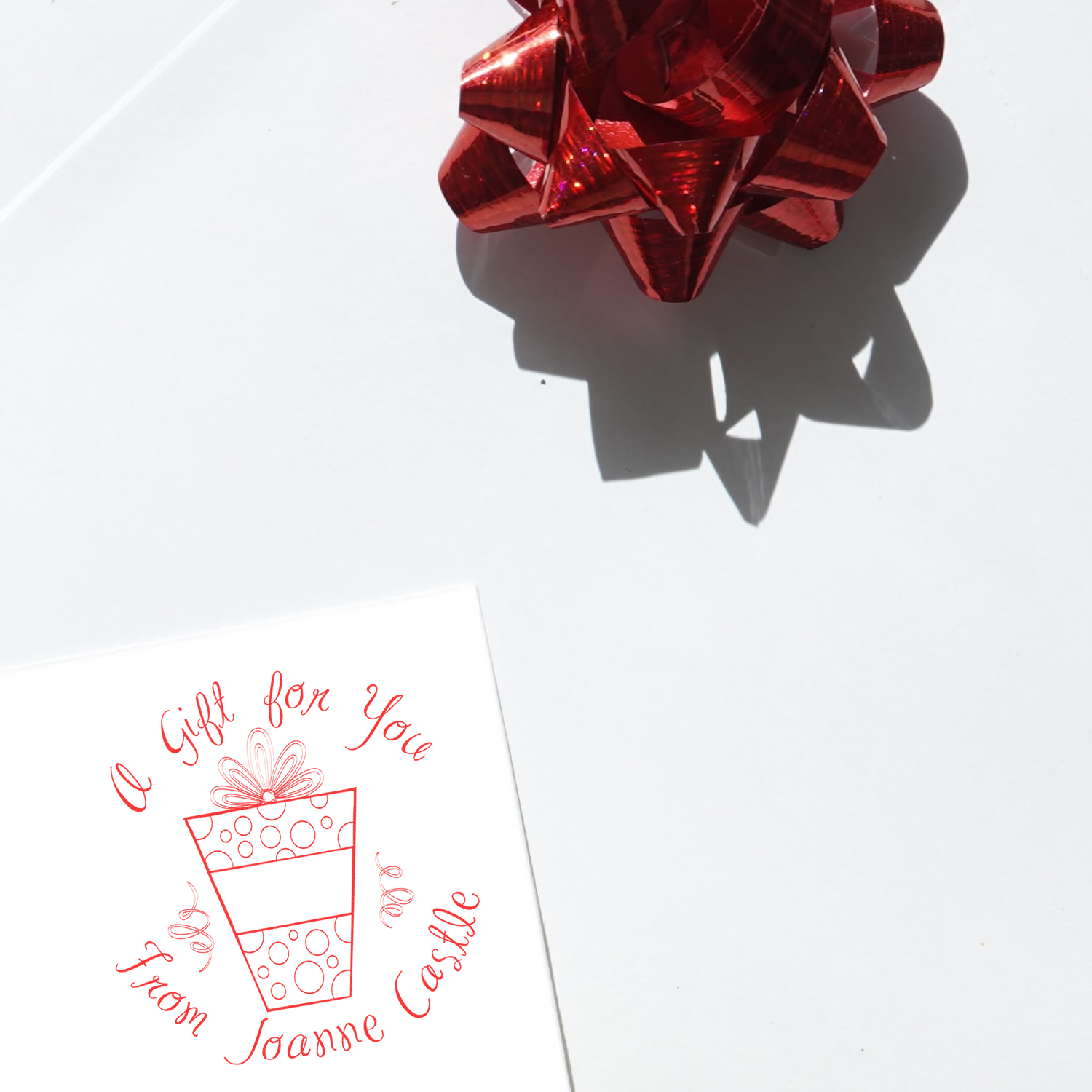 Custom rubber stamp reading A Gift for You from Joanne Castle on a greeting card, ideal for personalized gift packaging.