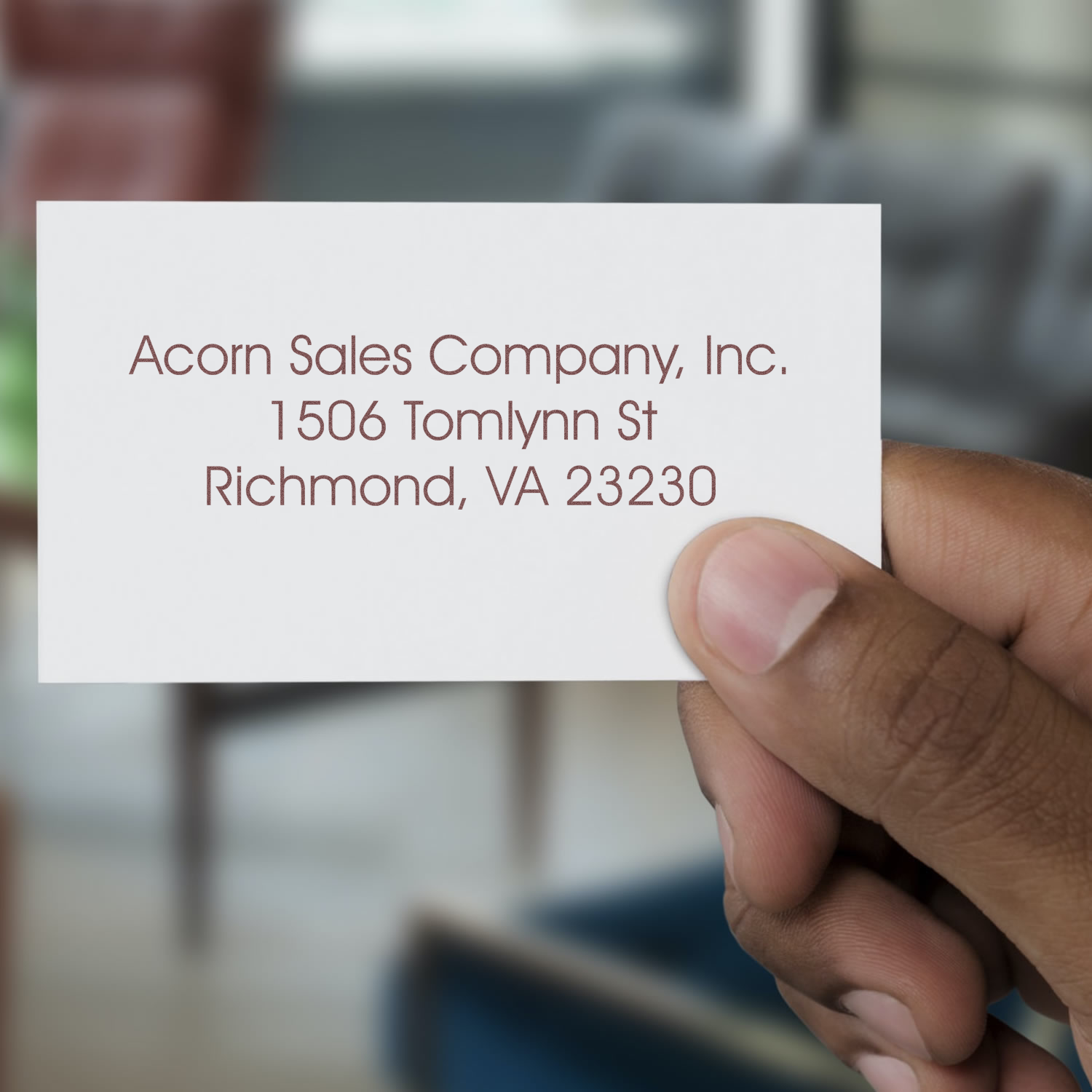 Hand holding a custom address rubber stamp sample card for business mailing and office branding.