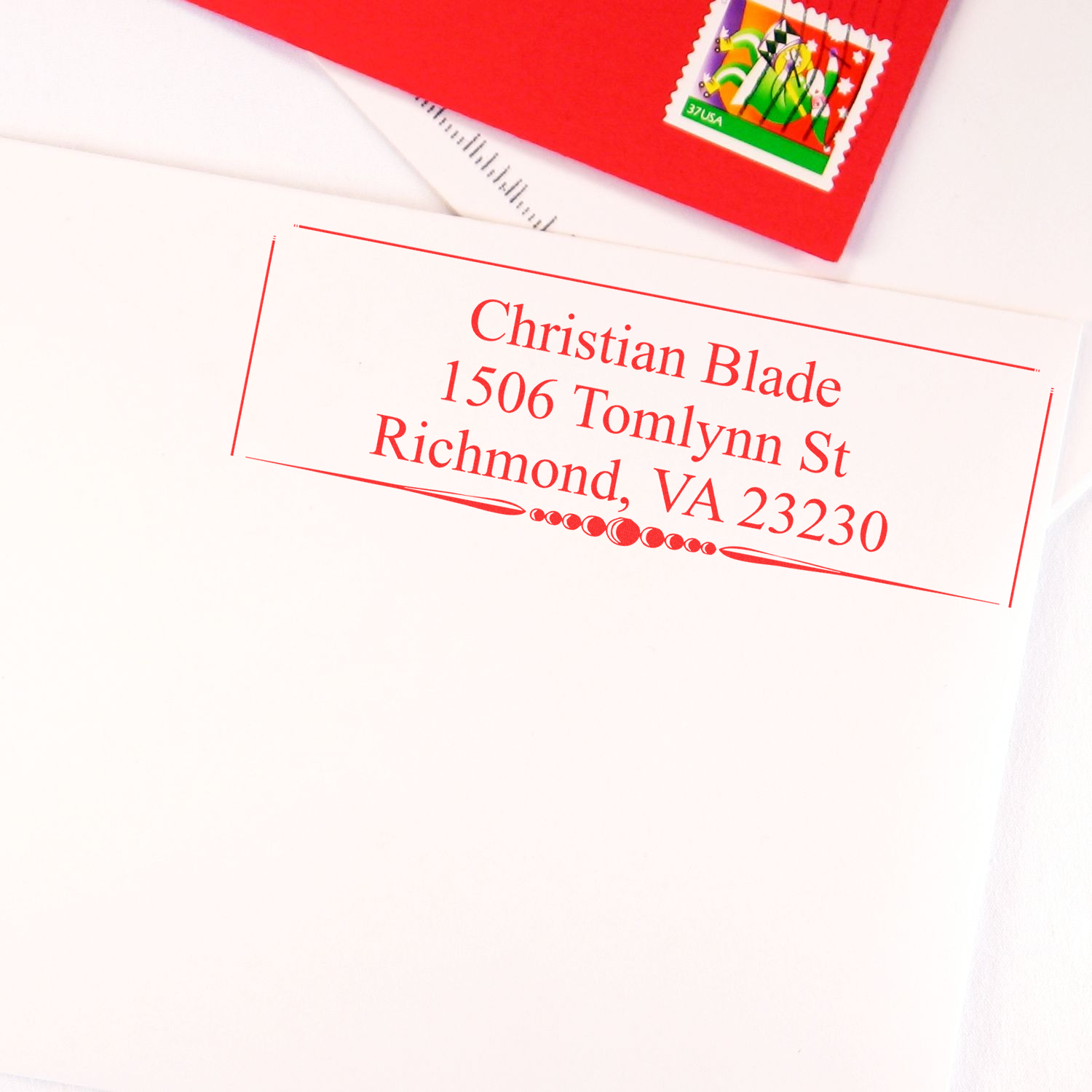 Custom return address rubber stamp on white envelope with red ink, ideal for personalized mail and stationery.