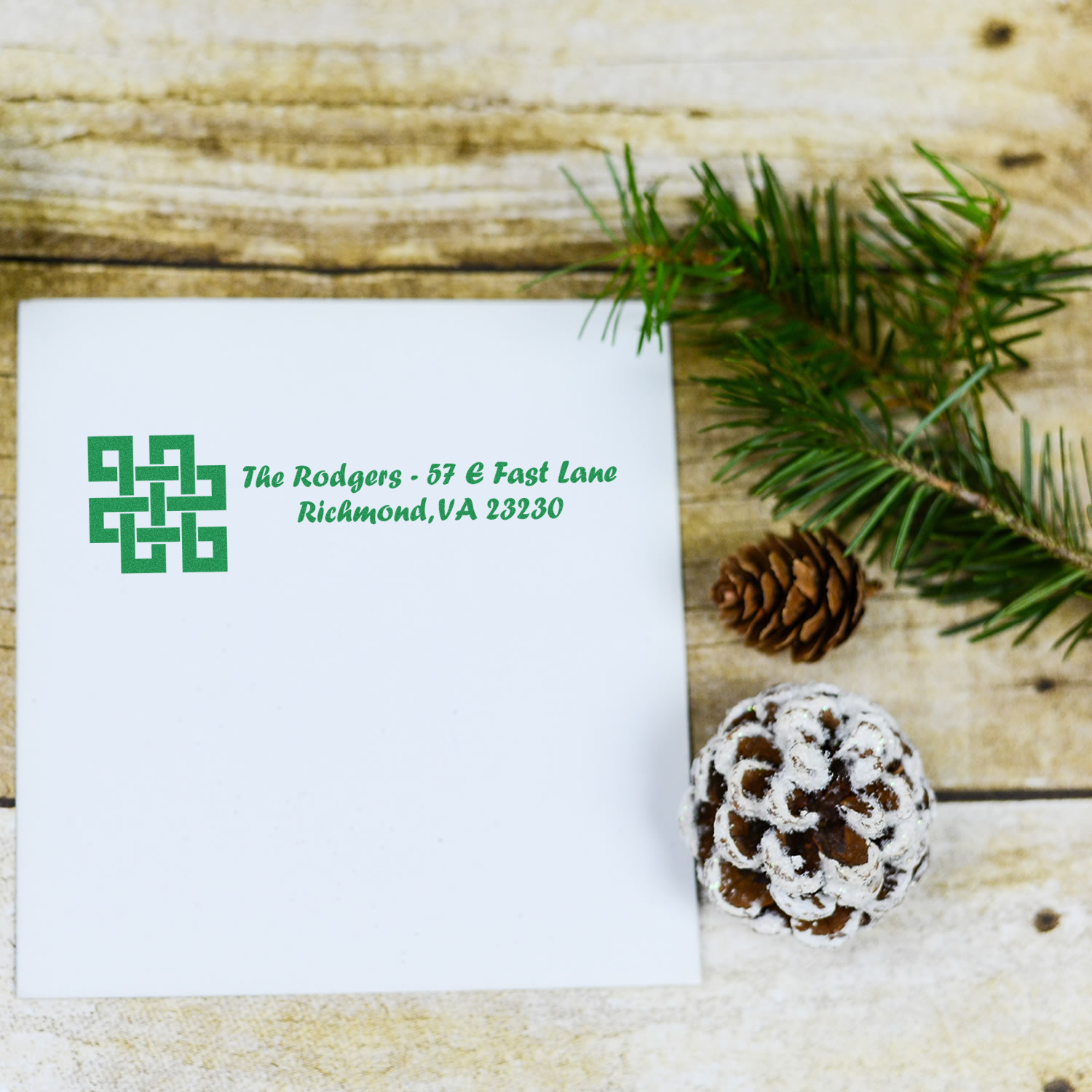 Custom return address rubber stamp on white envelope with green logo, ideal for holiday cards and business mail.