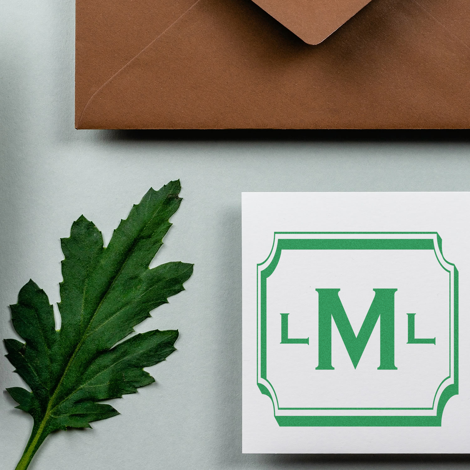 Custom monogram rubber stamp with green LM design on stationery, ideal for personalized envelopes and branding.