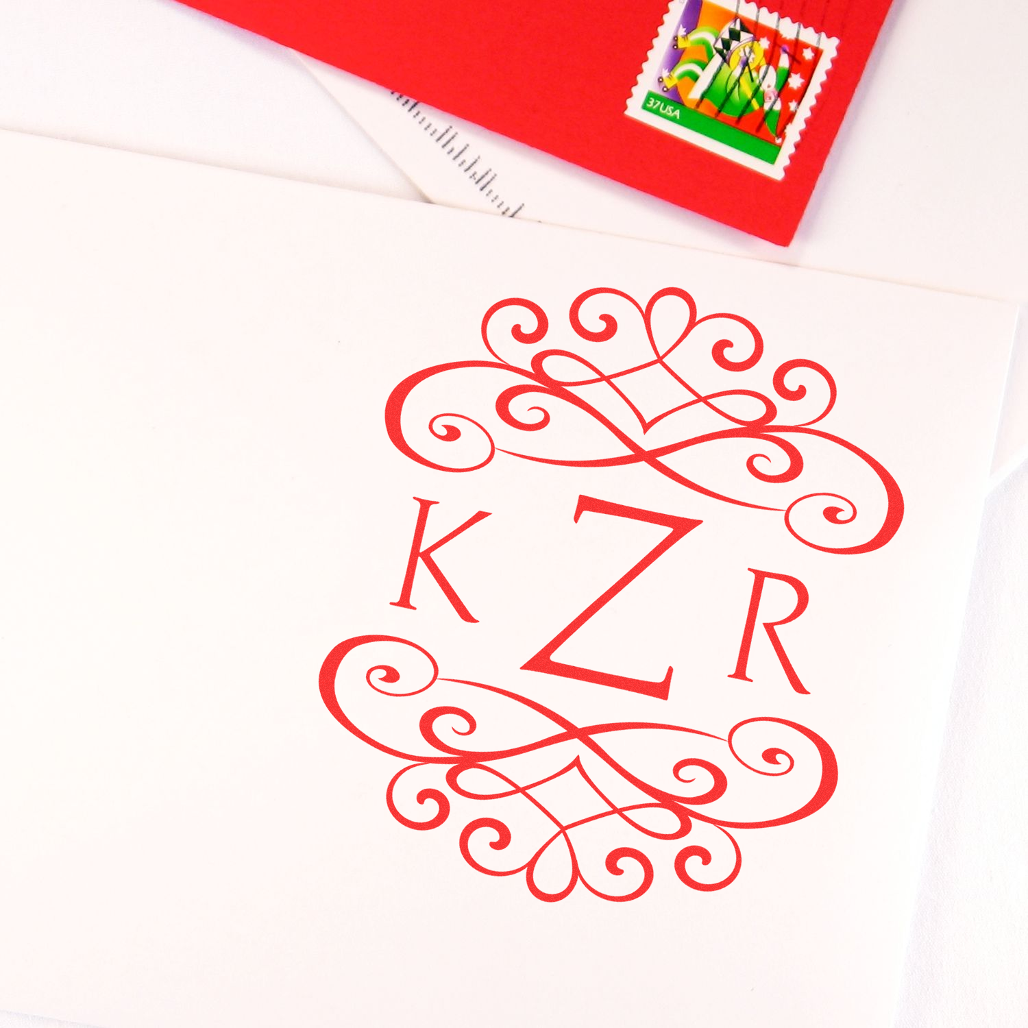 Red decorative monogram KZR on a mailed envelope, with a colorful US postage stamp in the upper corner for letter and card delivery.