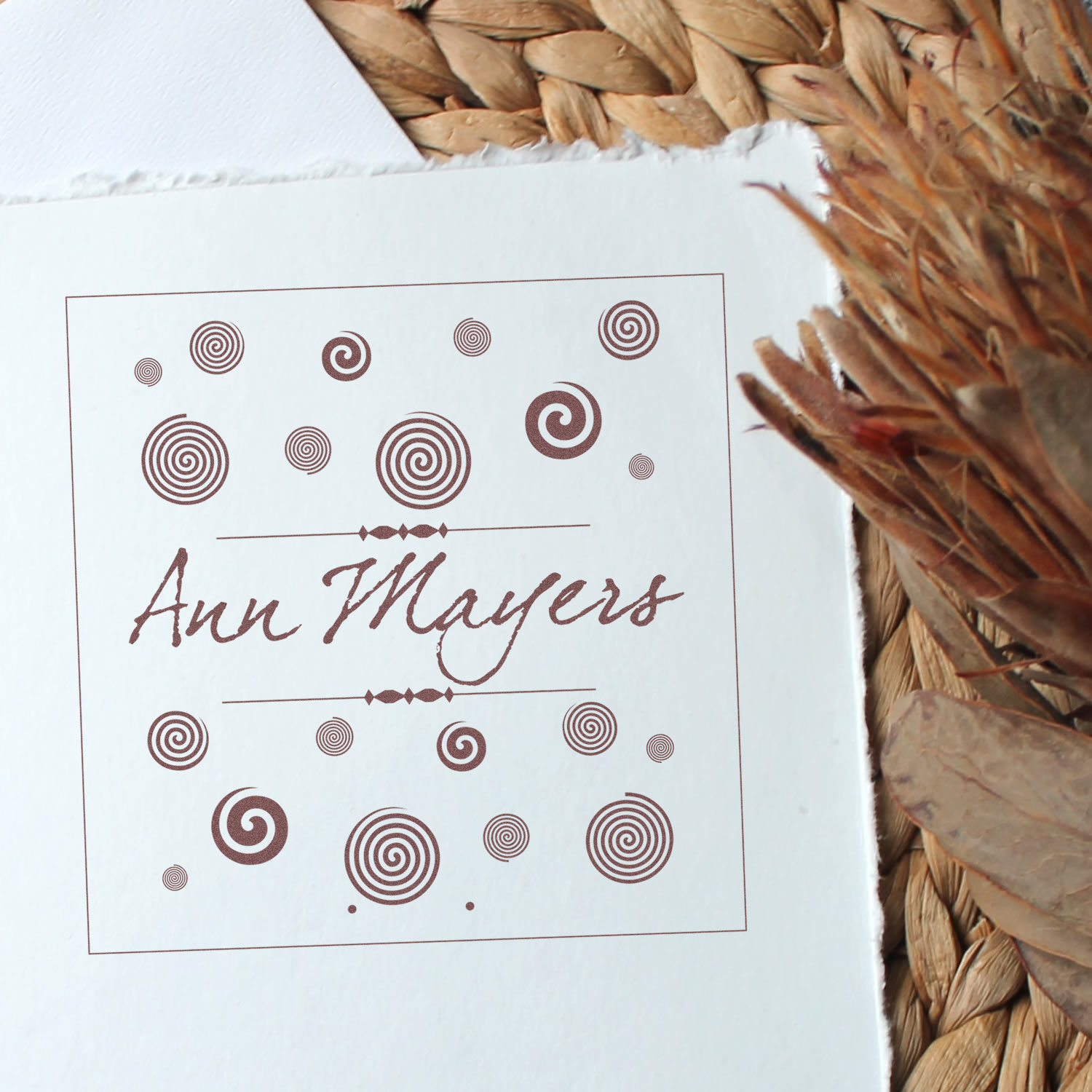 Personalized rubber stamp with Ann Mayers script name and decorative spiral accents.