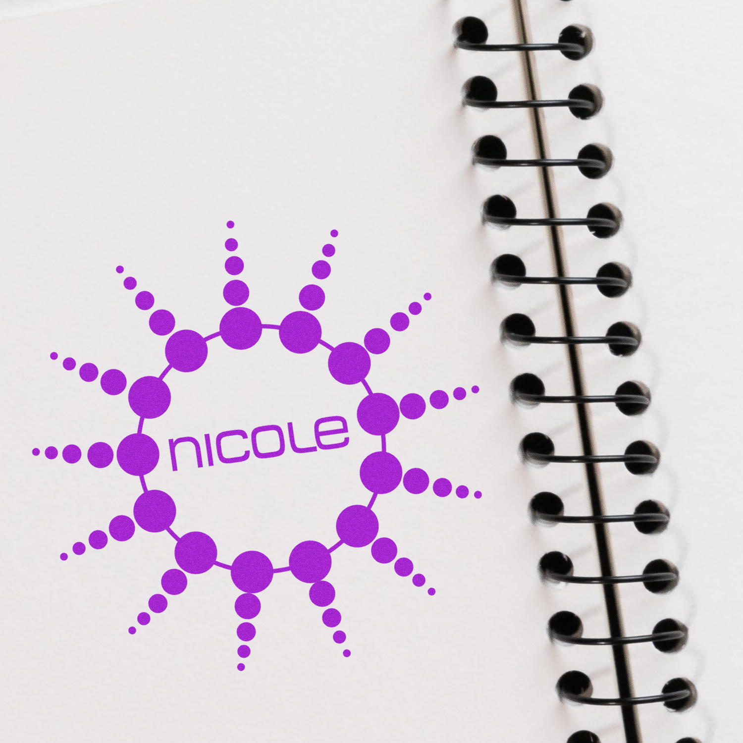 Nicole logo with purple molecule and atomic network graphic on a notebook with binder rings for science-themed journaling