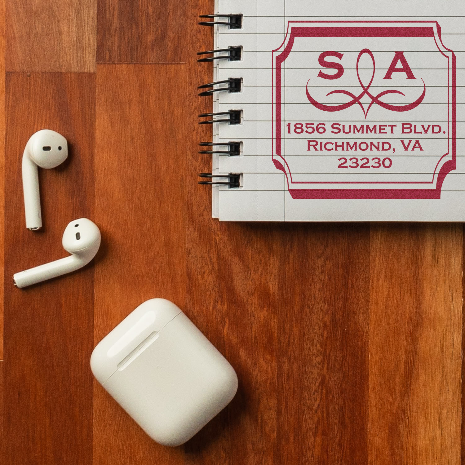 Custom rubber stamp logo with monogram and address stamped on notebook for stationery branding.