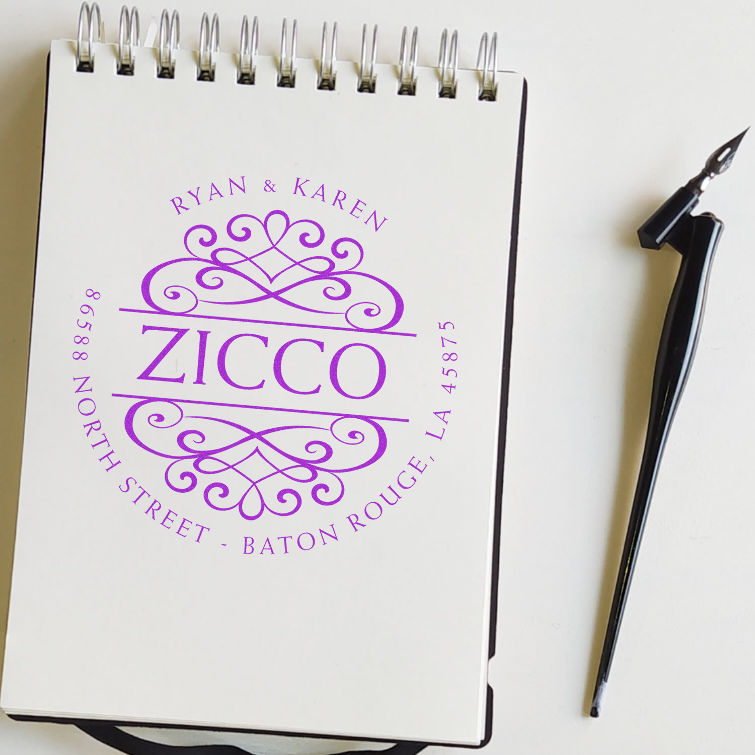Personalized wedding notebook cover with Ryan & Karen and Zicco purple lettering, Baton Rouge text, and pen beside it.
