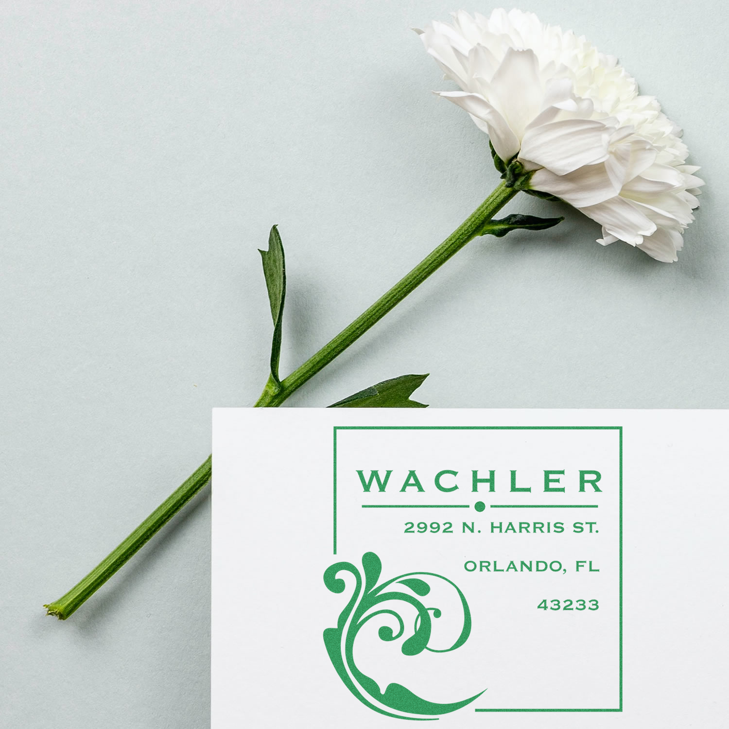 Custom return address rubber stamp with floral design and green ink on a white card.