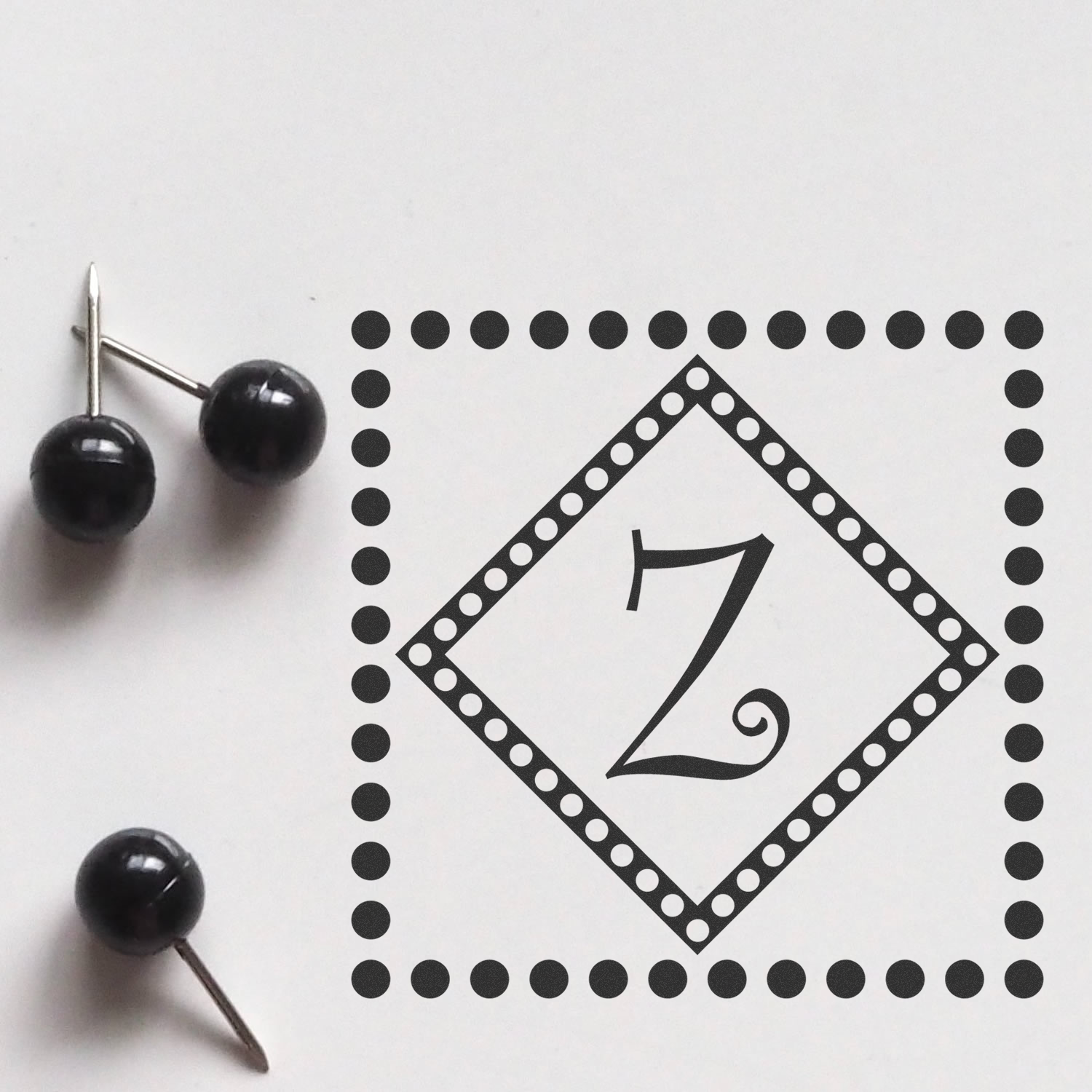 Decorative number 7 rubber stamp design with dotted diamond border and pushpin accents on white background.
