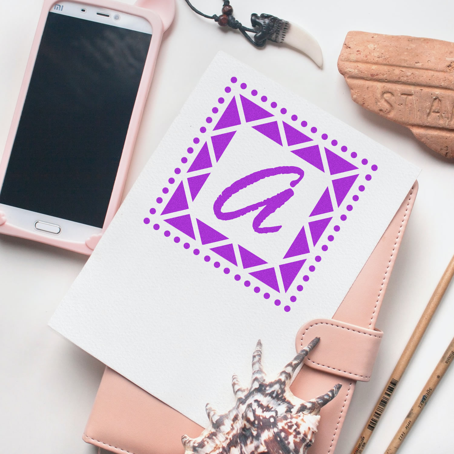 Custom purple geometric rubber stamp monogram on notebook, perfect for personalized stationery and branding.