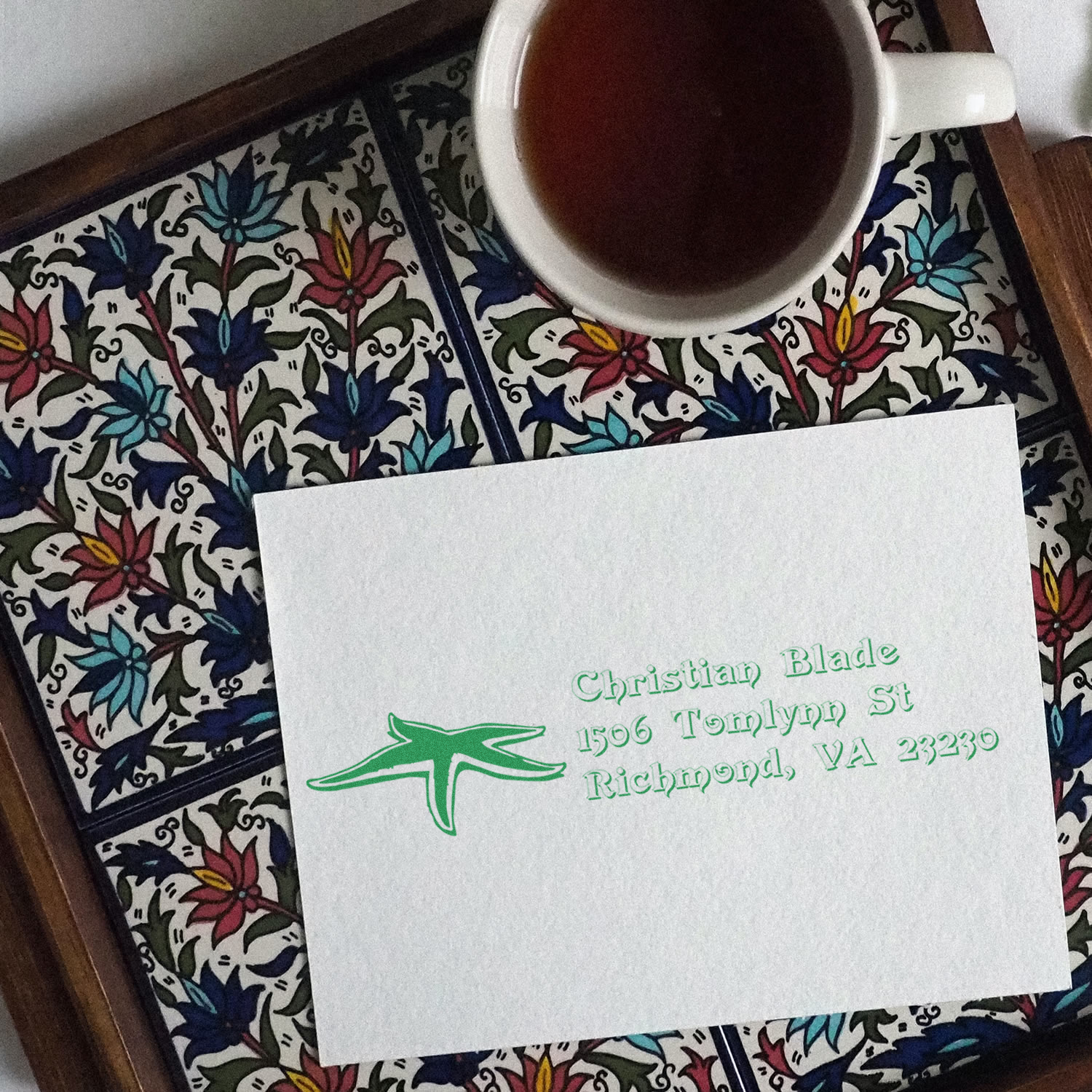 Custom rubber stamp return address on stationery, with green ink imprint beside a coffee cup for personalized mailings.