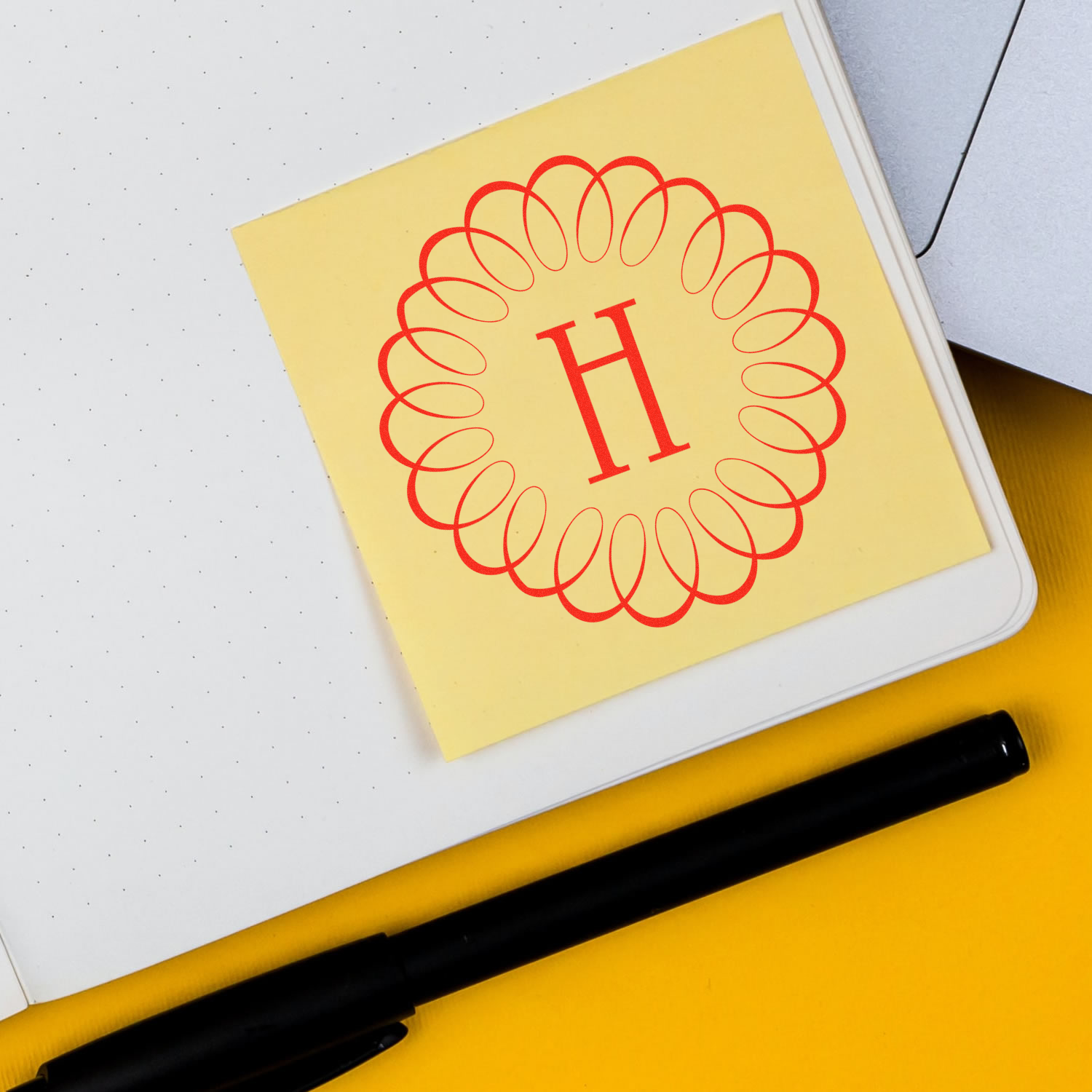 Custom rubber stamp monogram H with floral circle design on a yellow sticky note, ideal for branded stationery.