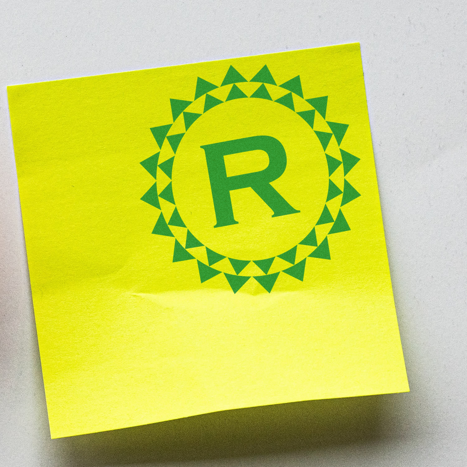 Custom monogram rubber stamp featuring a green R logo printed on a yellow sticky note.
