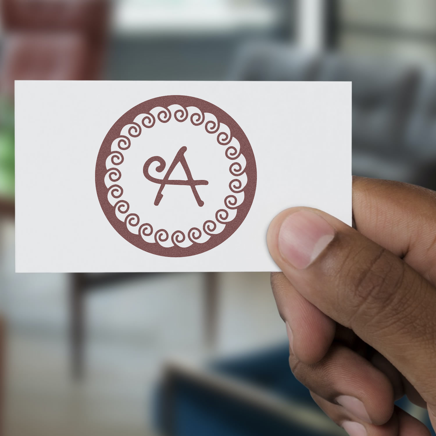 Custom rubber stamp design with decorative monogram letter A in a circular swirl border, displayed on a white card.