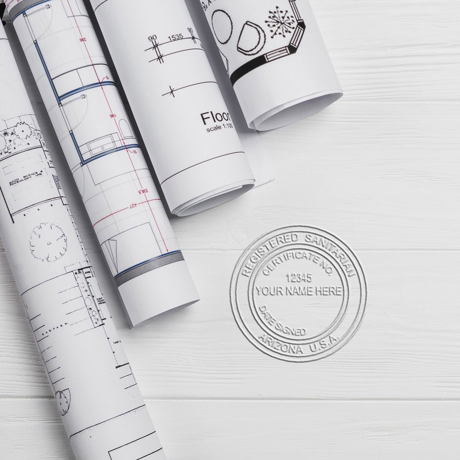 Rolled architectural blueprints with floor plan drawings and a stamped registered sanitary seal on a white desk.