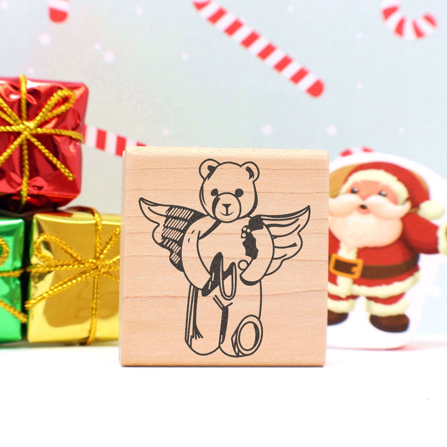 Wooden teddy bear angel stamp with Christmas gift boxes and Santa holiday decor background