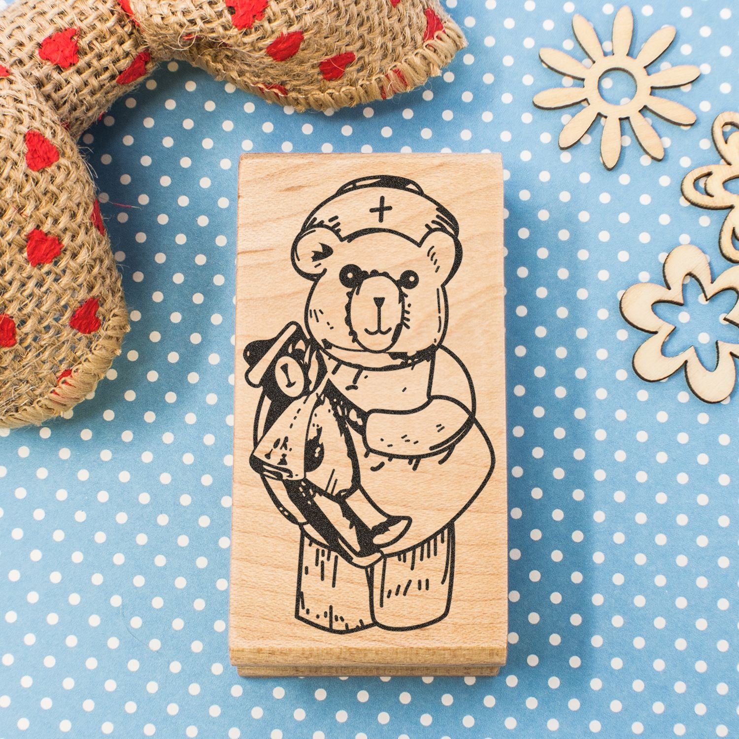 Wooden teddy bear nurse stamp on blue polka dot background with rustic craft decorations