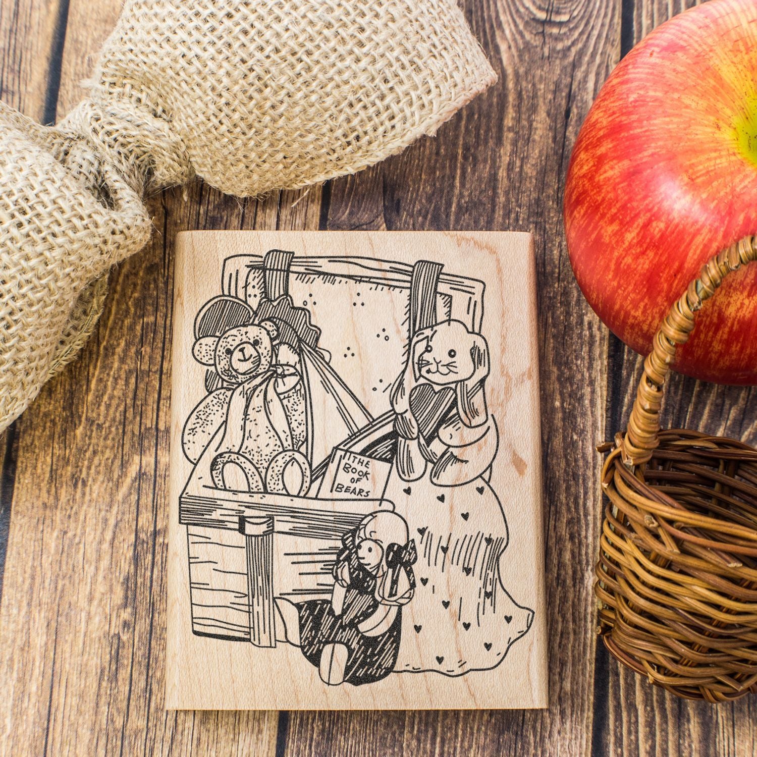 Wooden teddy bear engraving on rustic farmhouse decor with apple and burlap on a wooden background.