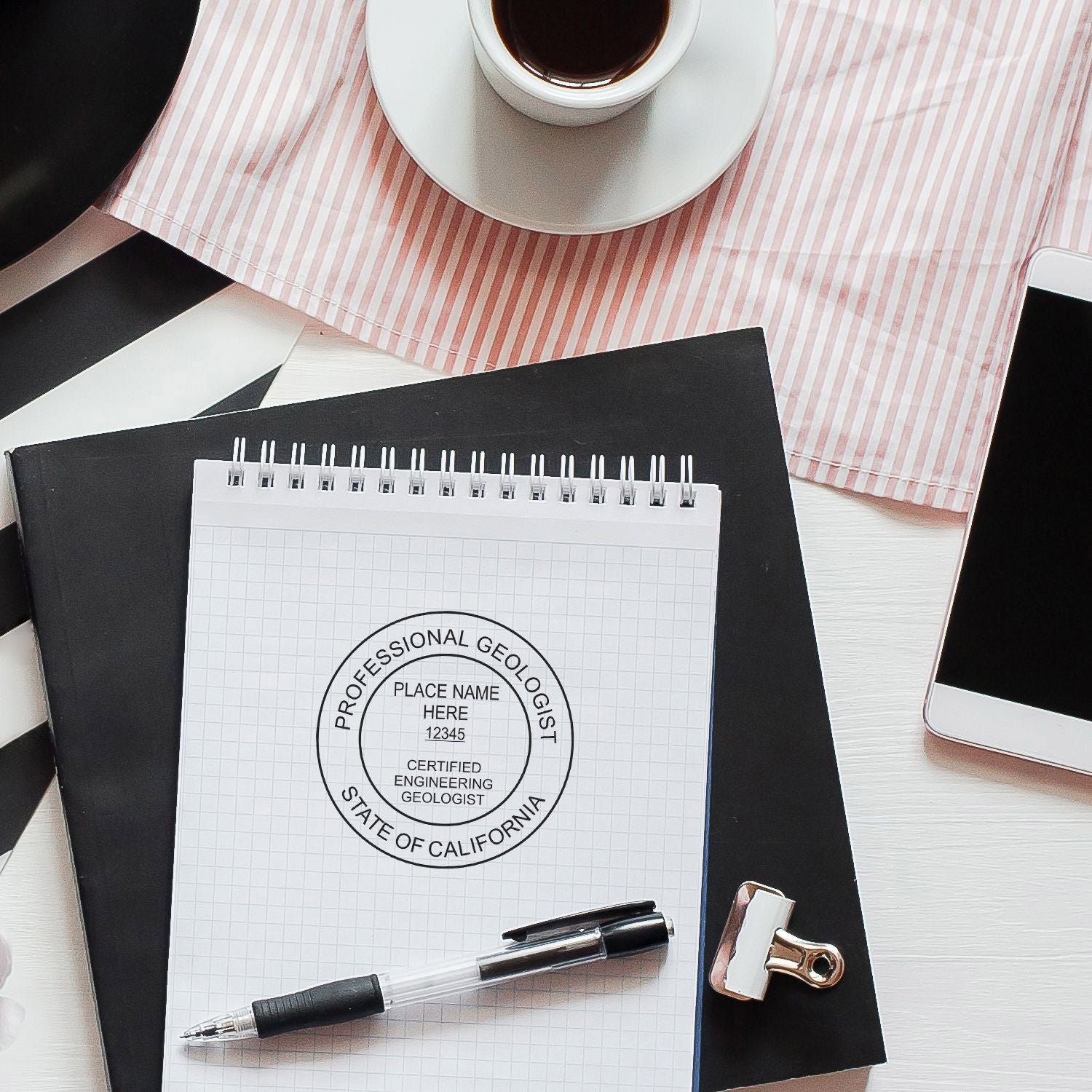 Professional geologist certification stamp on notebook with pen, coffee cup, and office desk workspace.