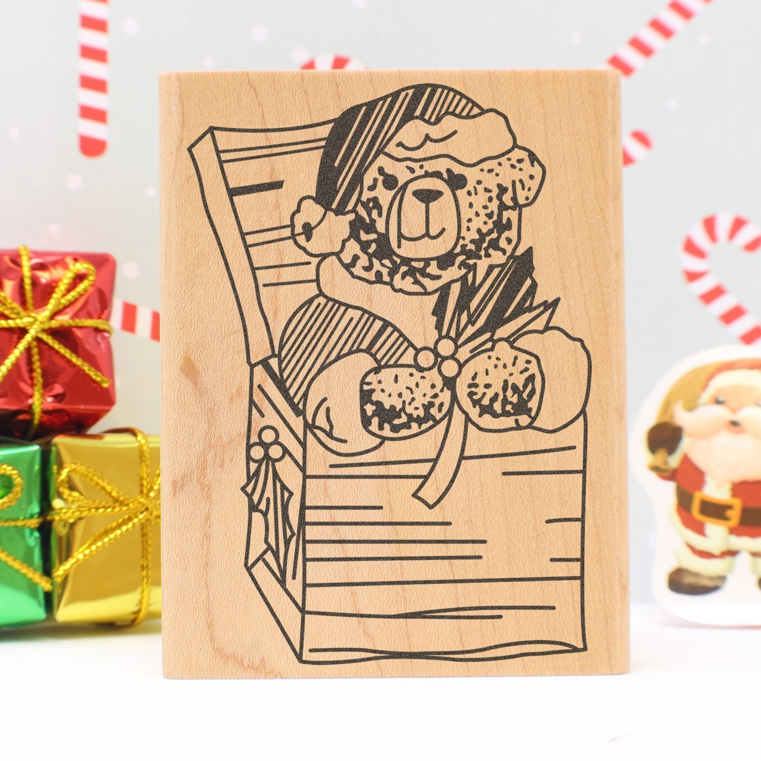 Cute teddy bear gift bag Christmas rubber stamp on wood block with holiday presents and candy cane background.