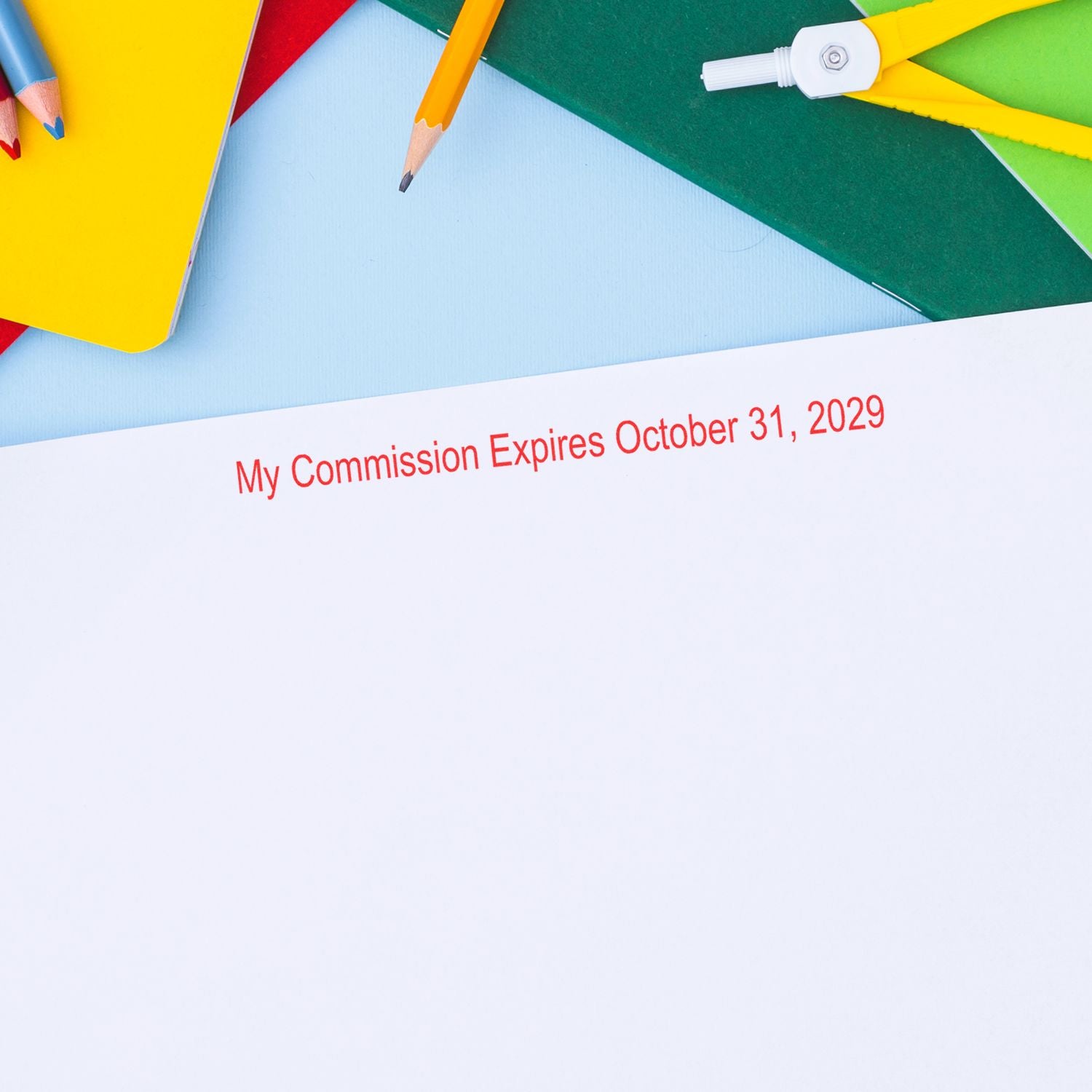 Colorful school supplies with paper reading My Commission Expires October 31, 2029 on a blue background.